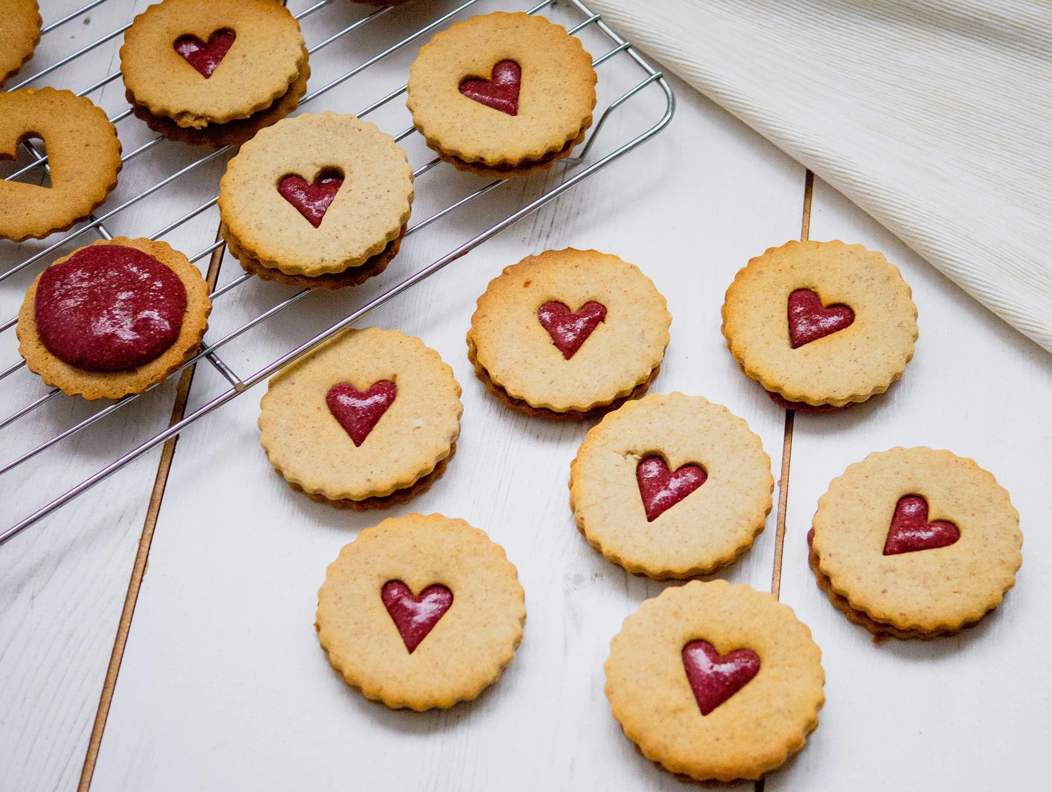 Baked and filled jammy dodgers on a cooling tray and a white table