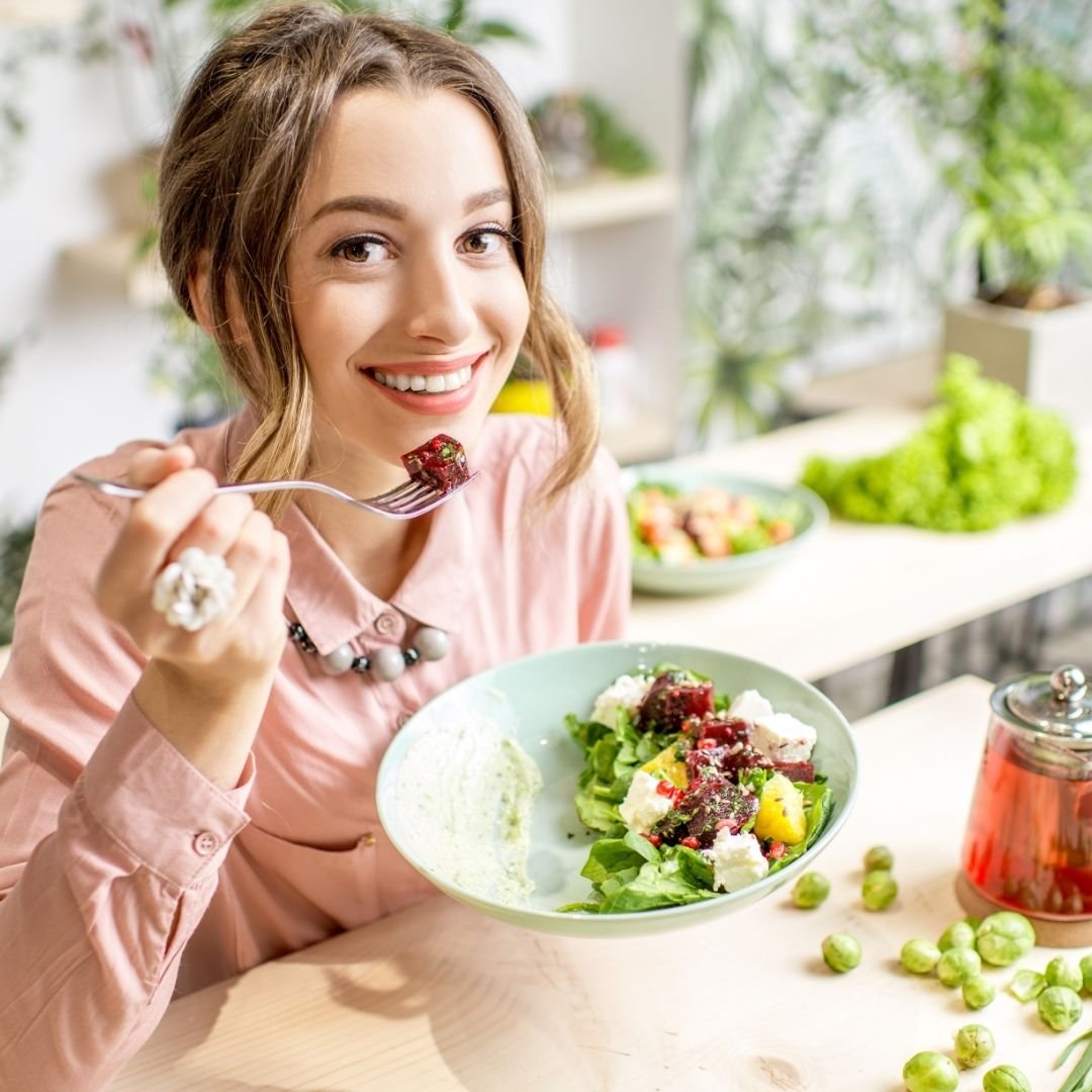 a young pretty girl happily eating a bowl of salad