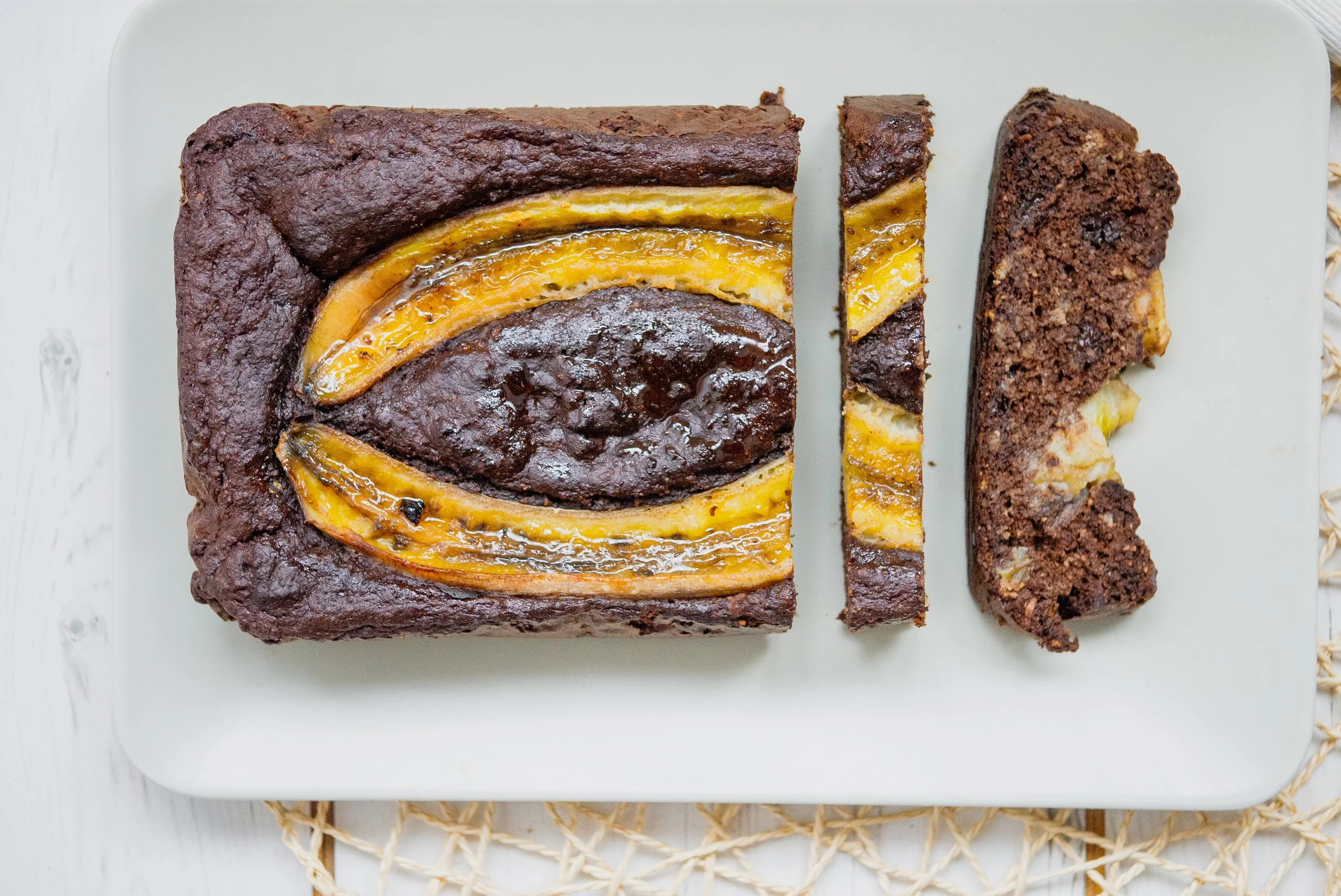 2 slices of chocolate banana bread next to a whole loaf