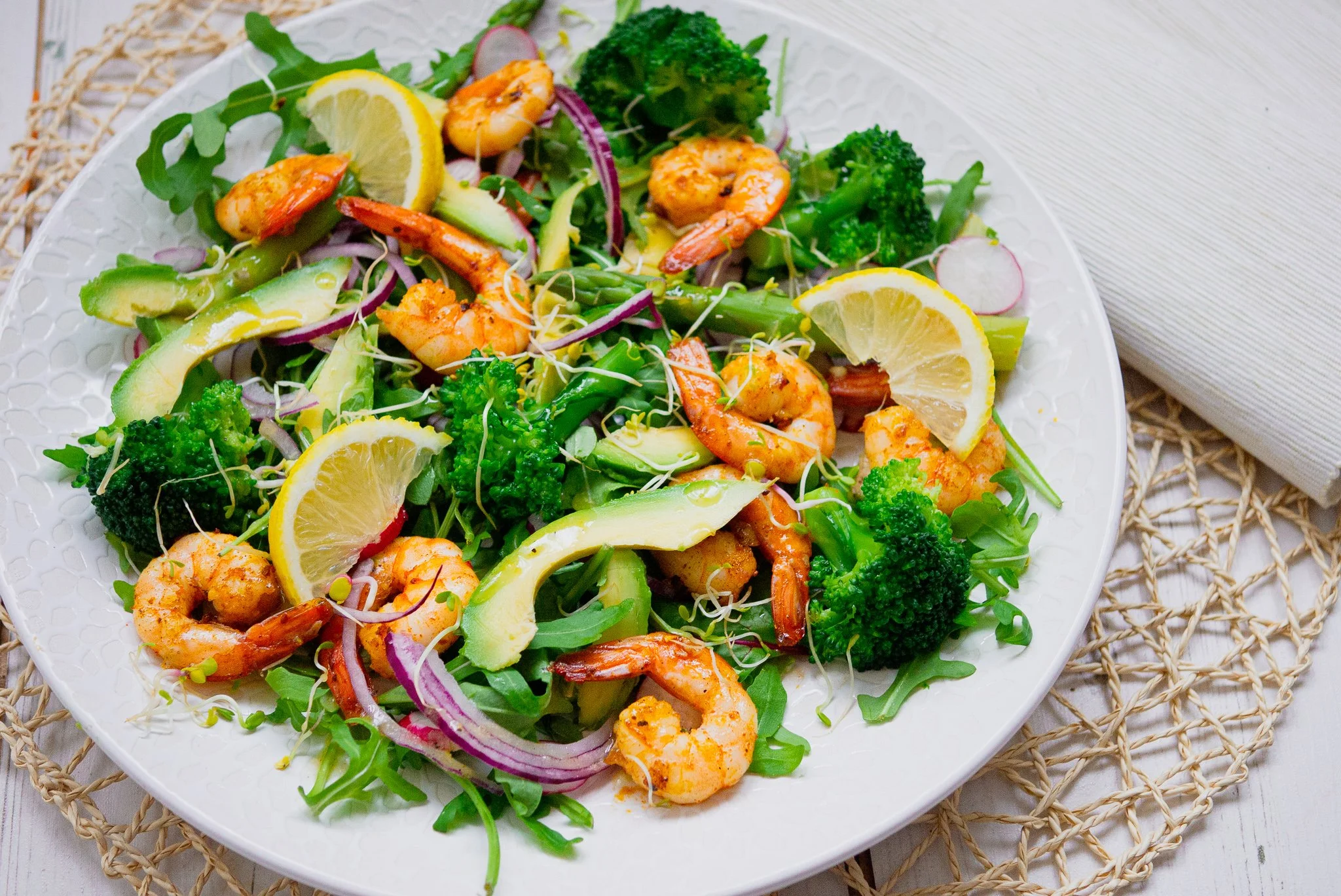 White full of fresh salad ingredients with Cajun spiced prawns and dressing