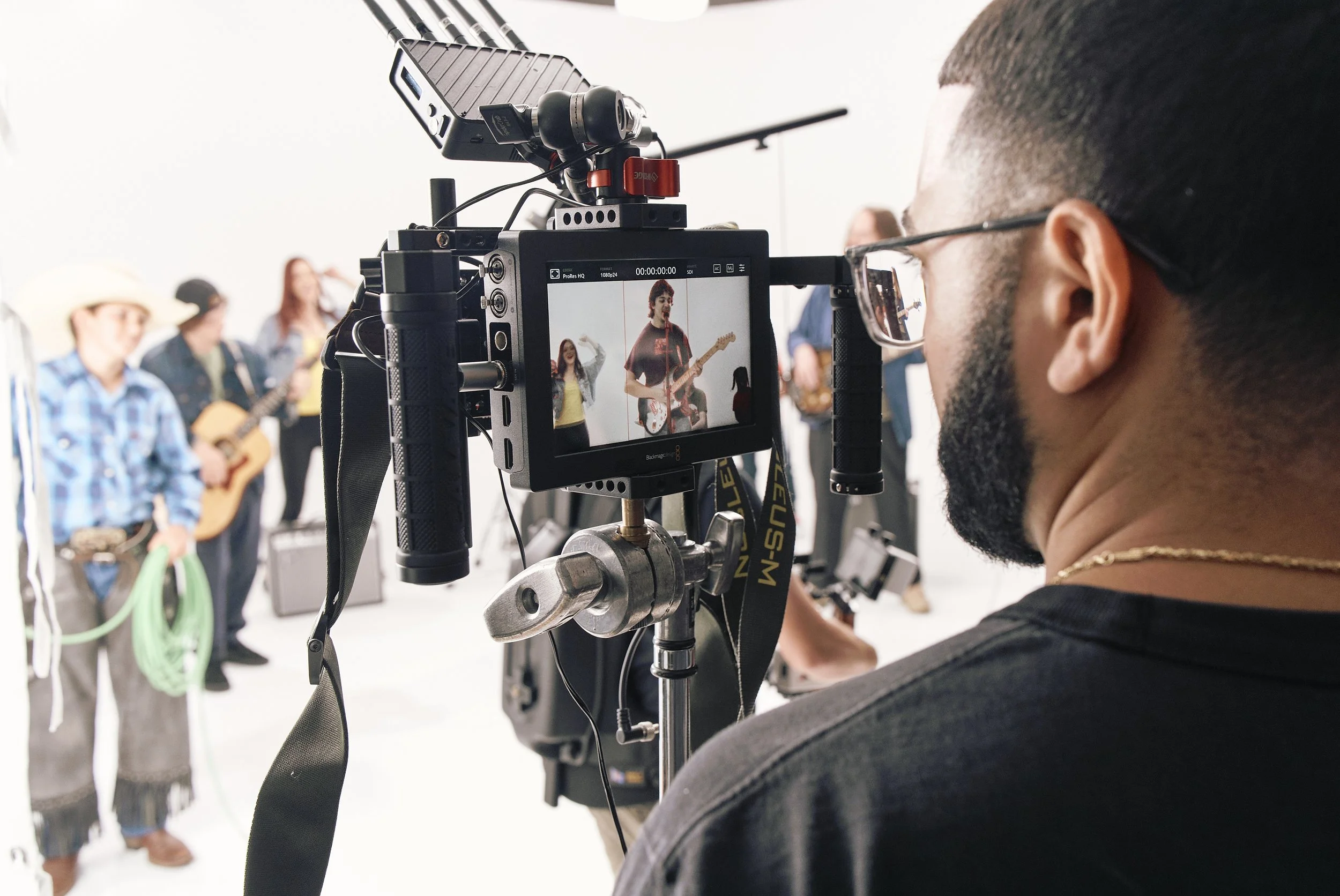 Man looking into a monitor on a white cyc sound stage.