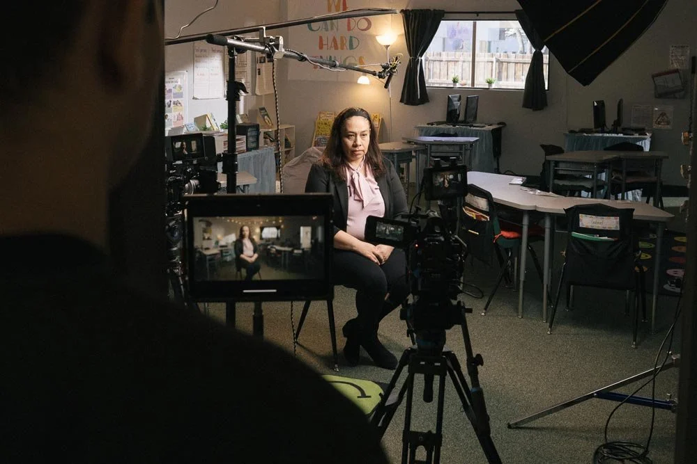 Woman being interviewed in front of a camera and light for a documentary