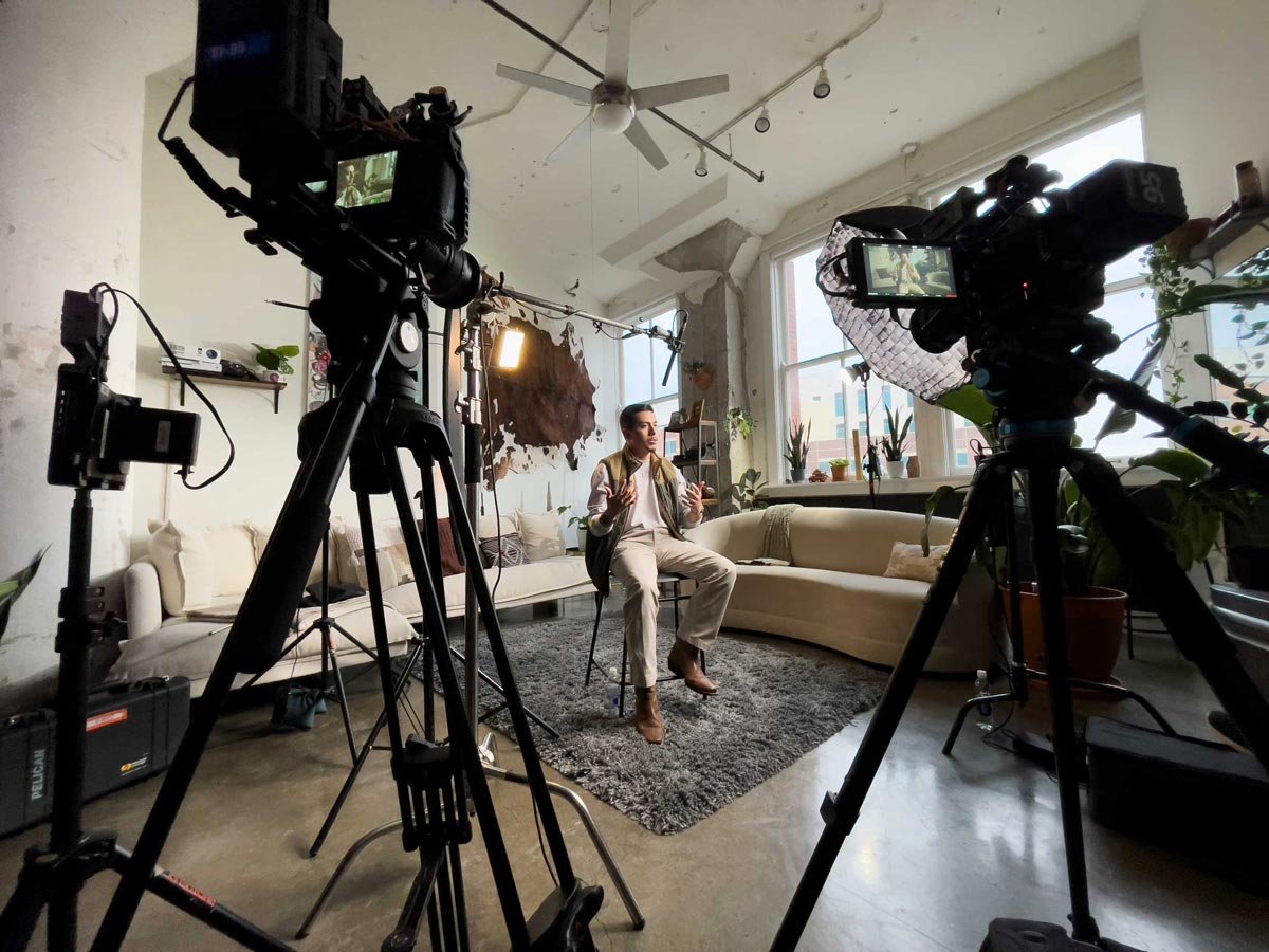 Young man giving an interview in front of two videography cameras.