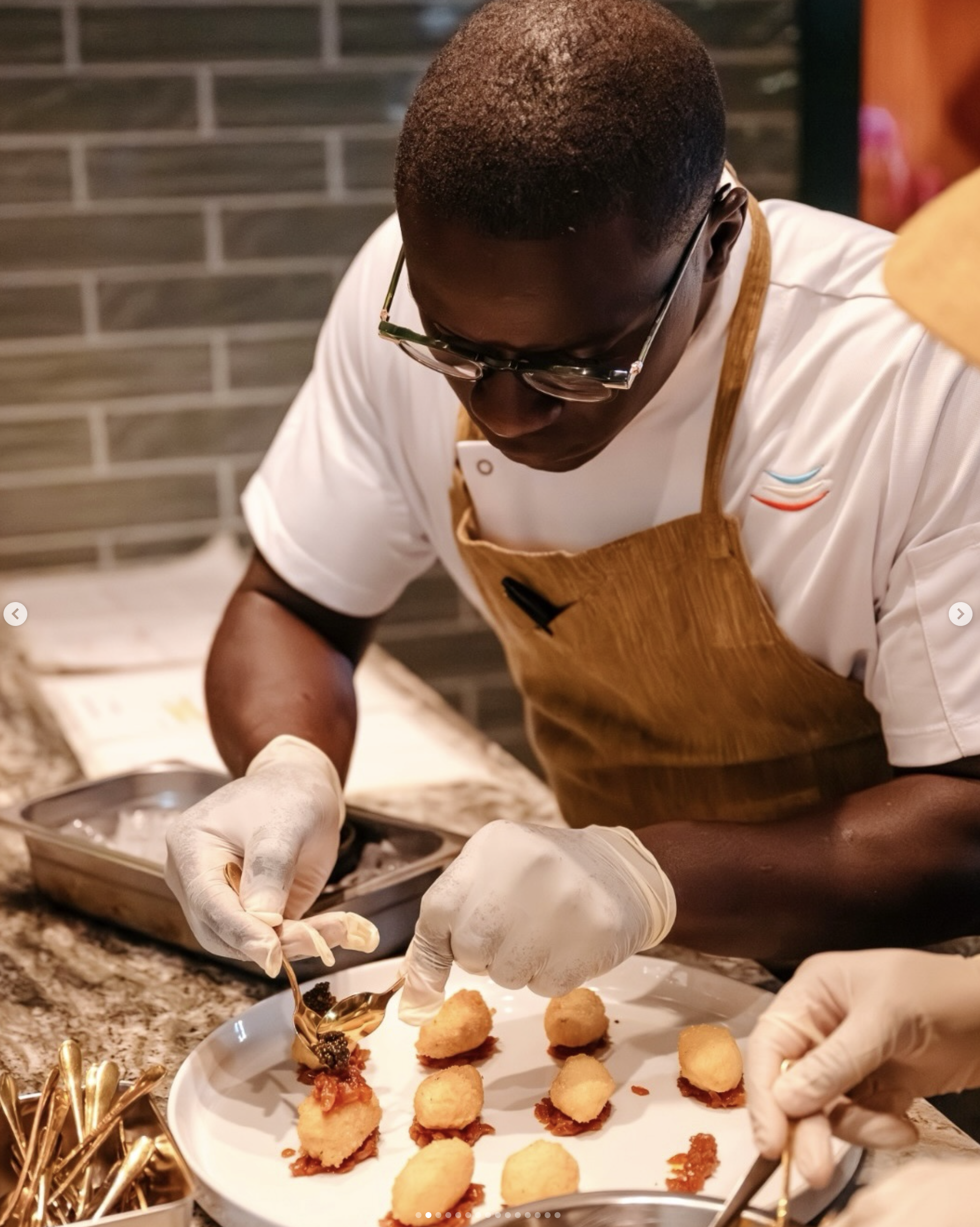 A chef wearing glasses and gloves plating caviar on a dish