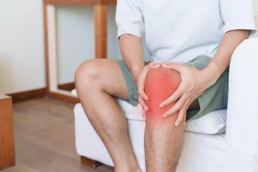 Man holding his knee, with the joint highlighted in red to show arthritis pain