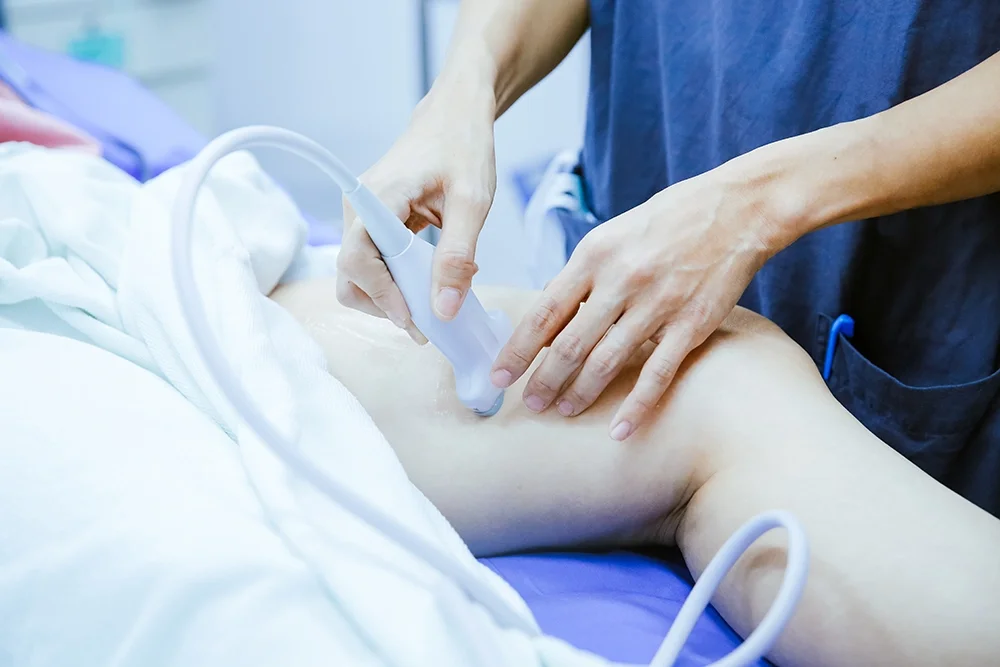 Clinician using an ultrasound probe on a patient's leg before a vein procedure