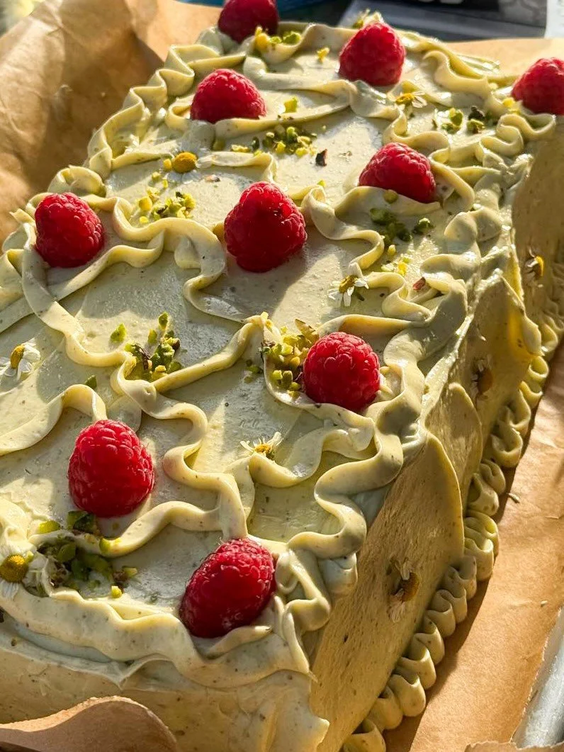 Pistachio, raspberry and cream cheese cake. Pistachio sponge cake filled with cream cheese and sweetened condensed milk mousse and fresh raspberries, covered in pistachio white chocolate icing.