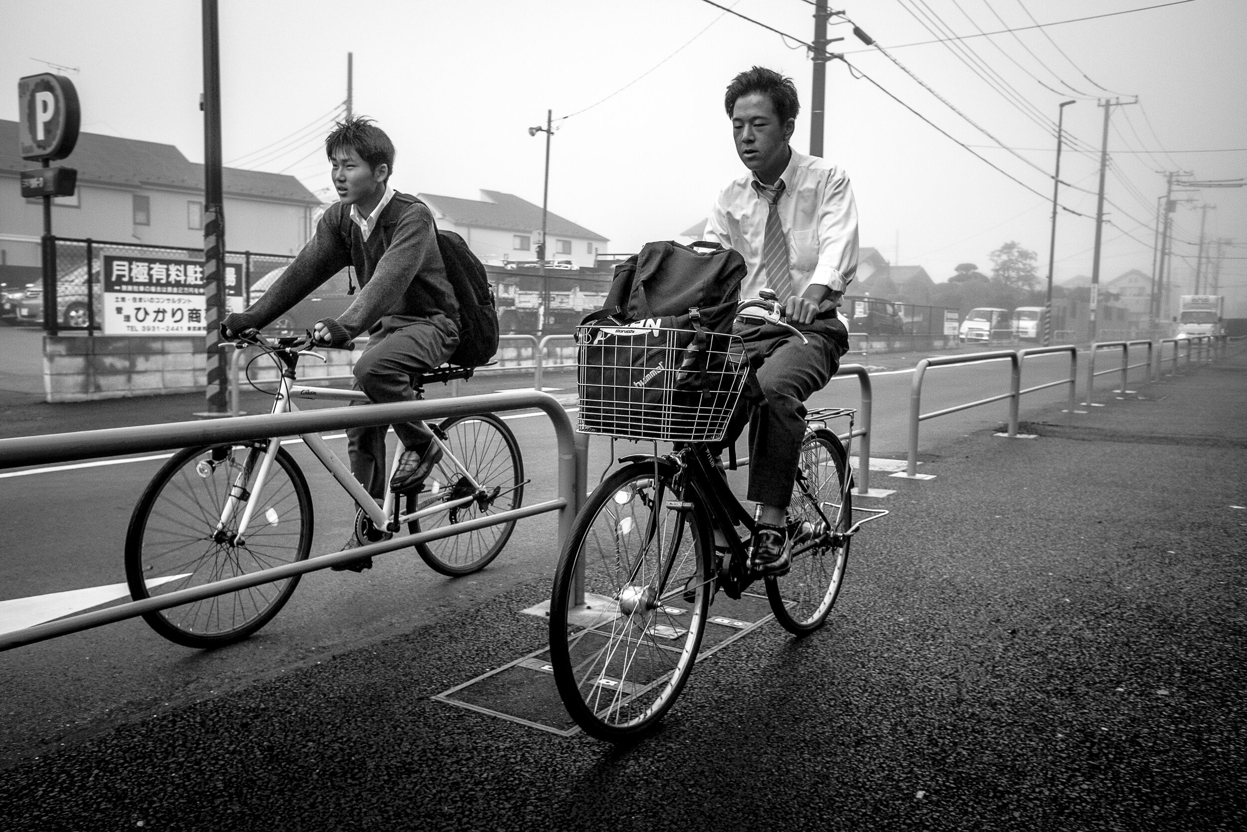 Dos homes en bicicleta en un dia boirós, en blanc i negre.