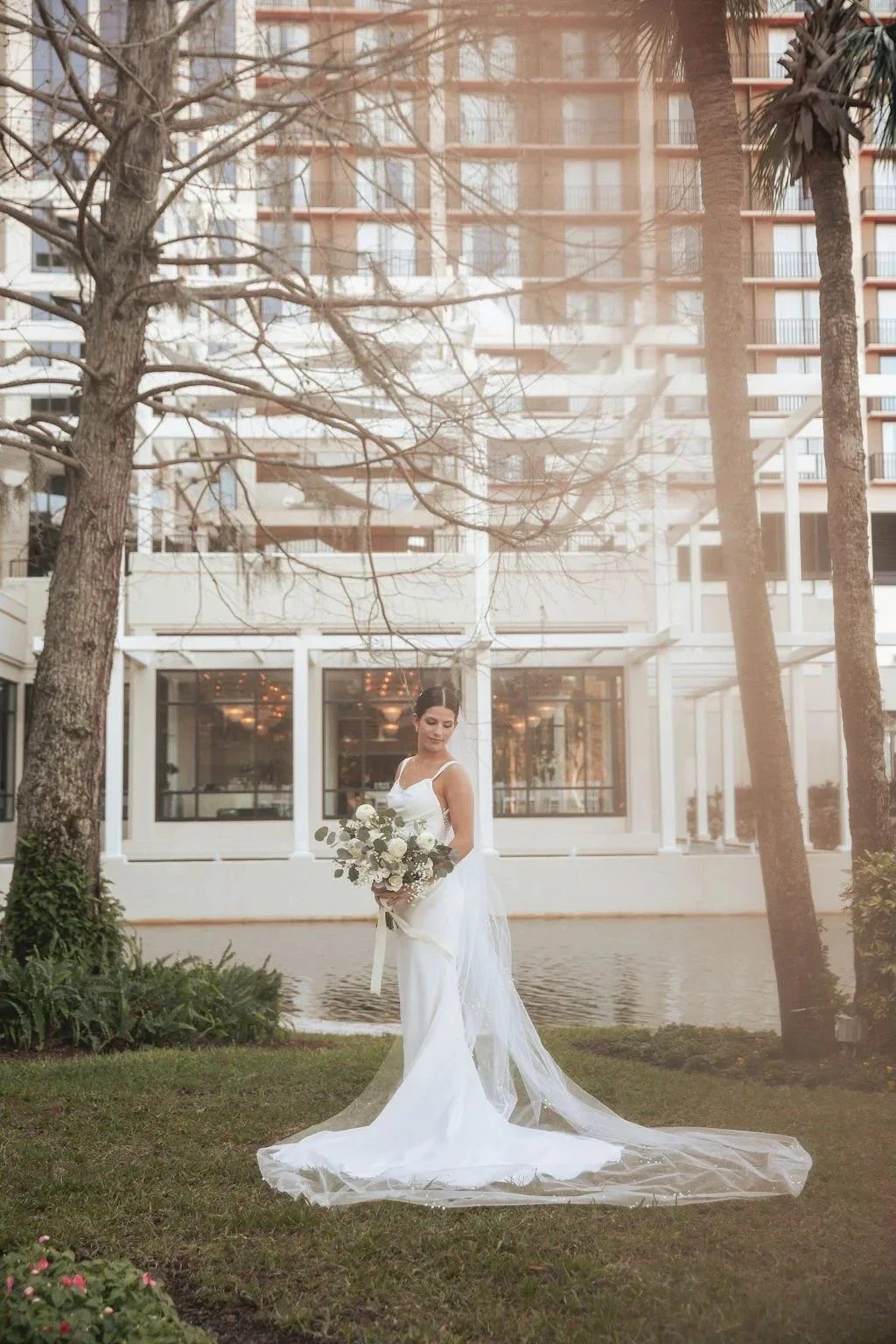 Bride in elegant white wedding dress holding a white rose and eucalyptus bridal bouquet, created by Orlando wedding florist JF Events & Flowers