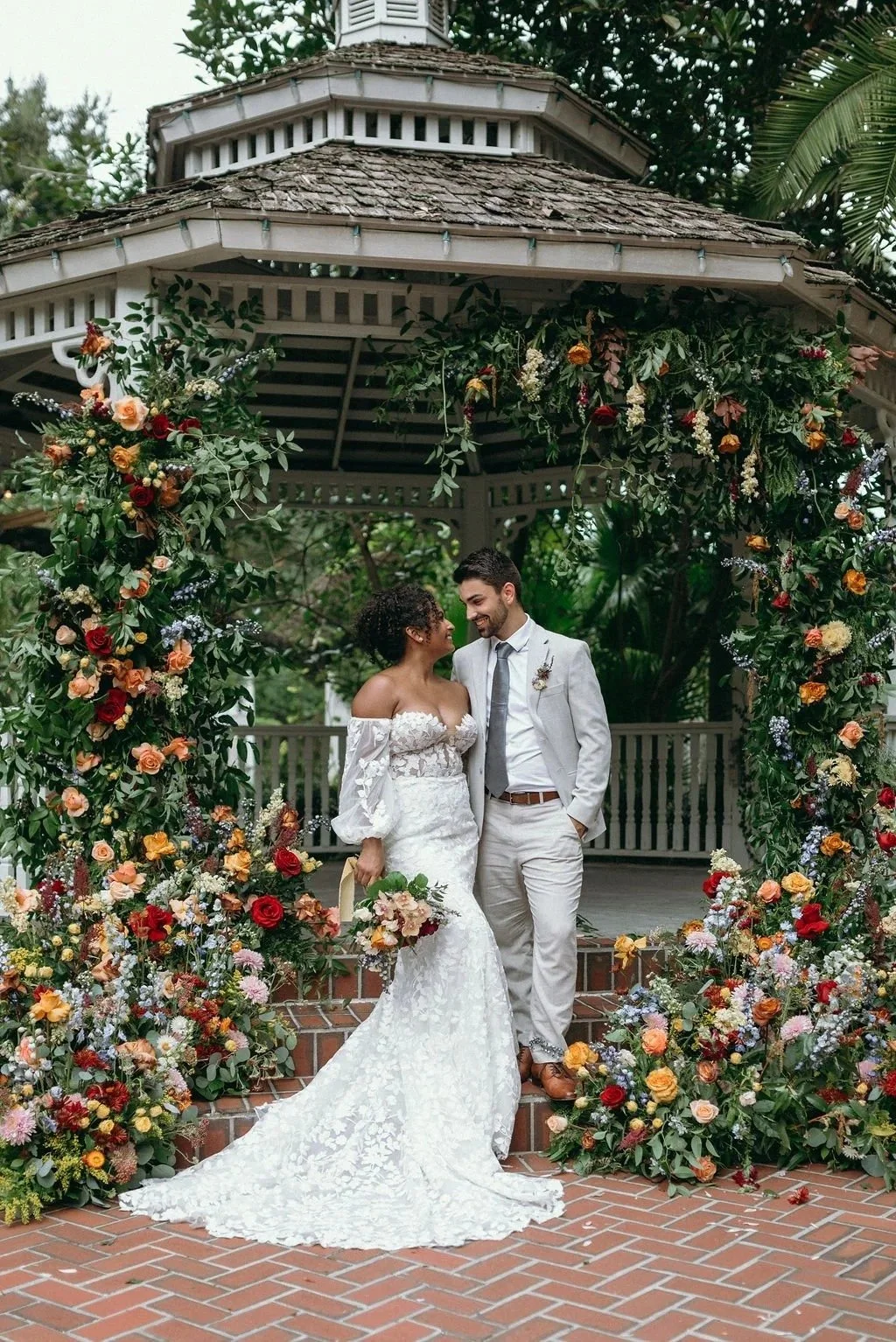 bride and groom under a pergola surrounded by autumn inspired floral arrangements by JF Events & Flowers, an Orlando wedding florist and day-of coordinator