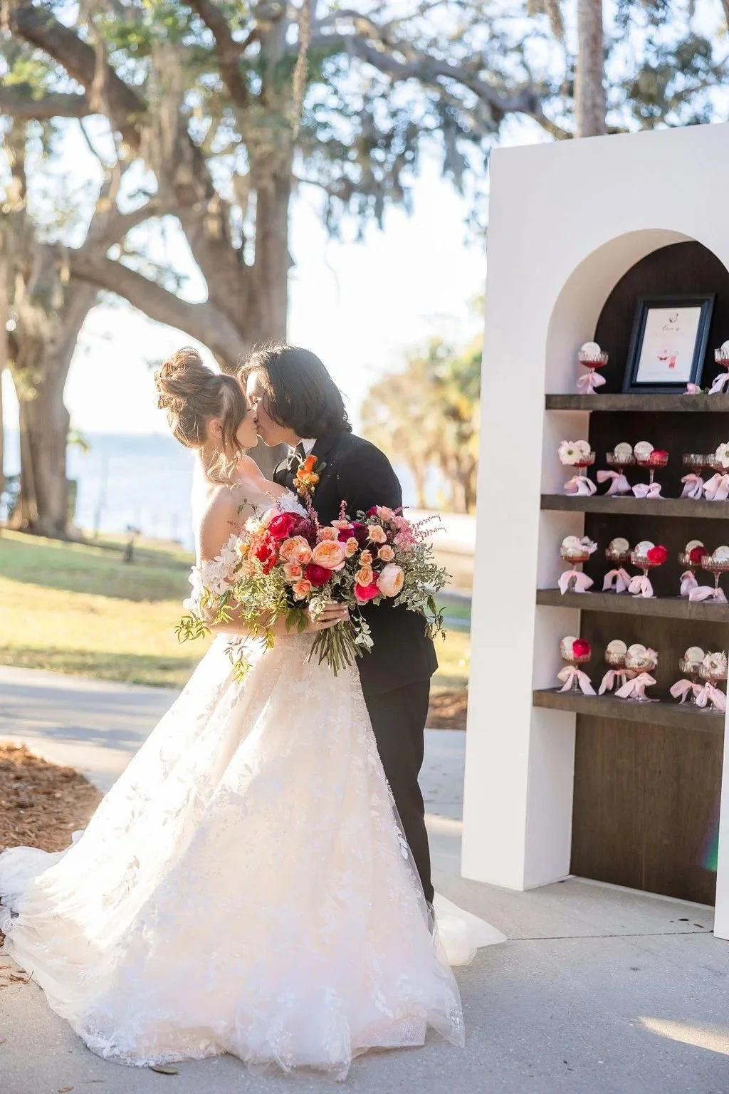 bride and groom kissing while holding a lush bridal bouquet with pink flowers, created by Orlando wedding florist JF Events & Flowers