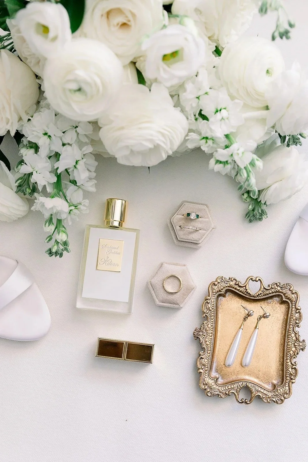 flat lay photo of perfume, ring boxes, and a gold tray with wedding jewelry surrounded by white florals by JF Events & Flowers, an Orlando wedding florist and day-of coordinator