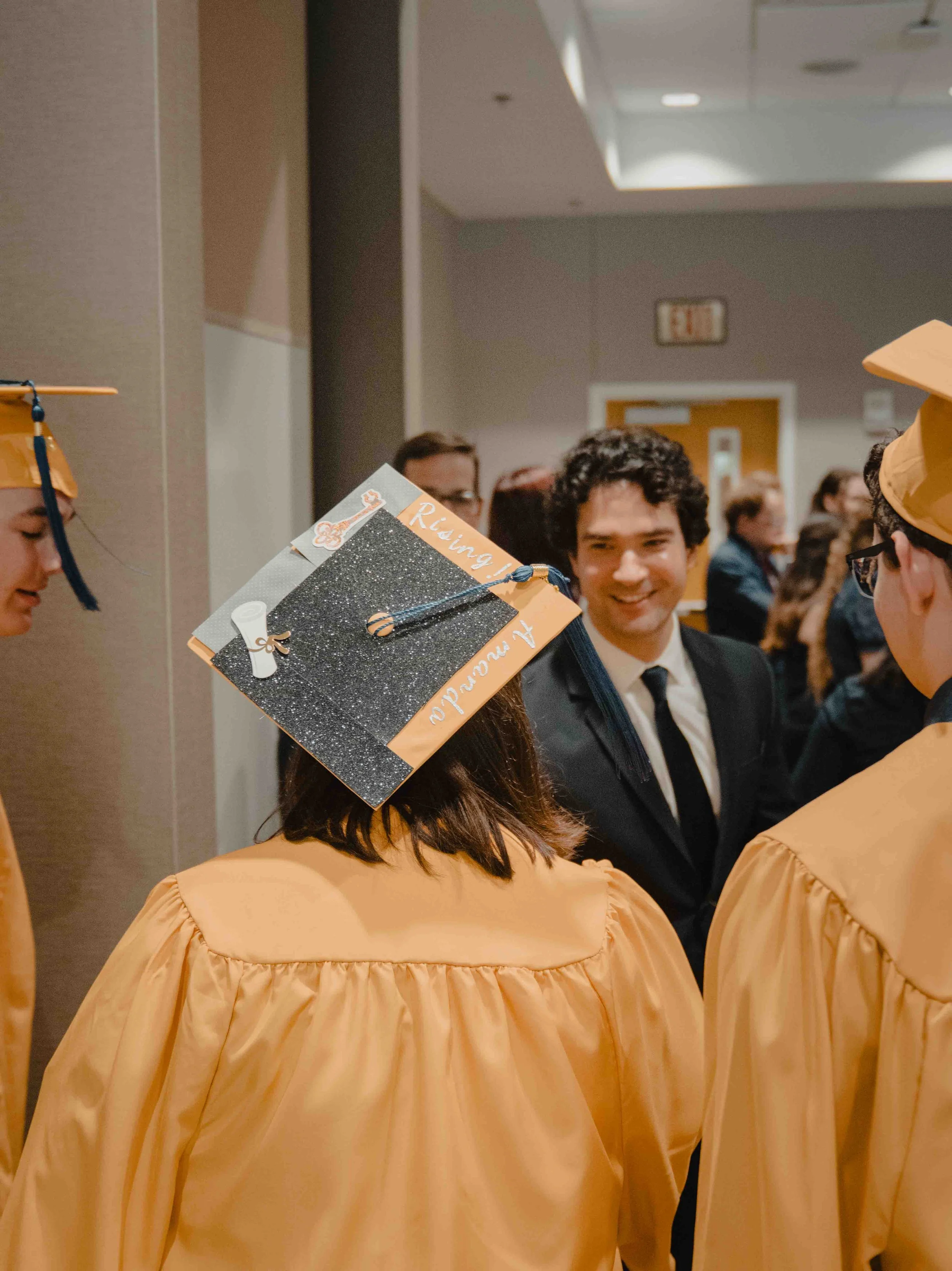 Graduates in caps and gowns at a graduation ceremony, smiling and celebrating.