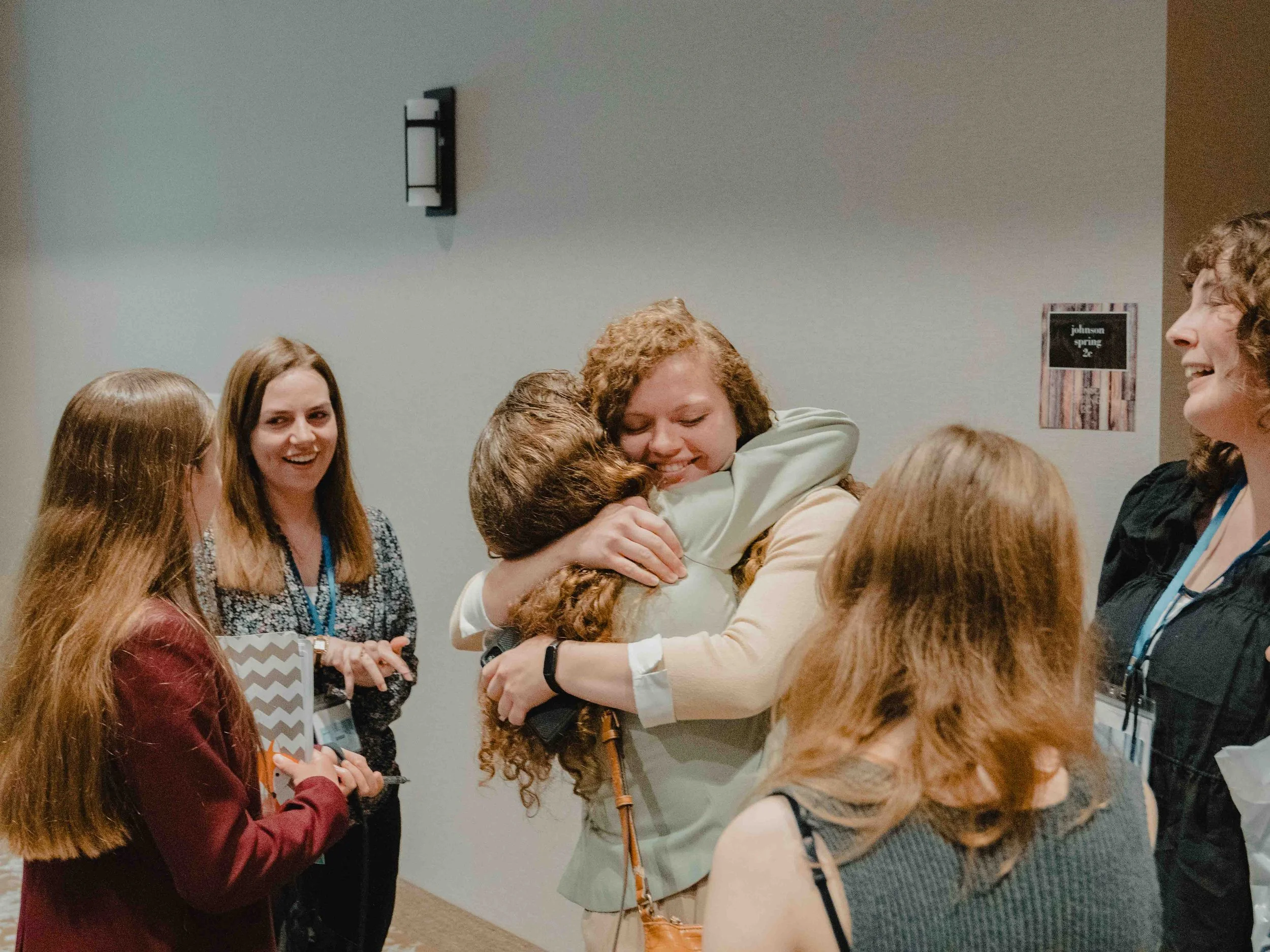 Group of people hugging and smiling at each other indoors.