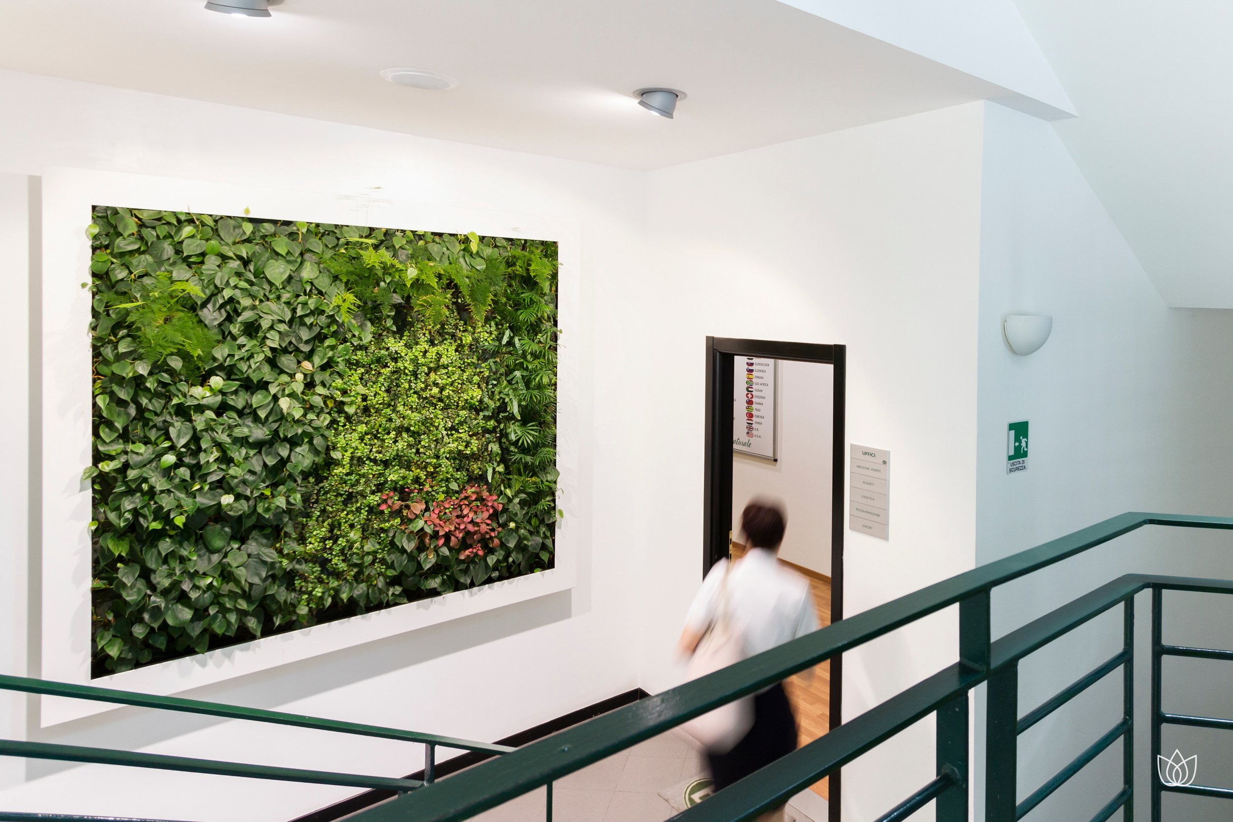 Interior of a building with decorative green wall and a person walking down the stairs