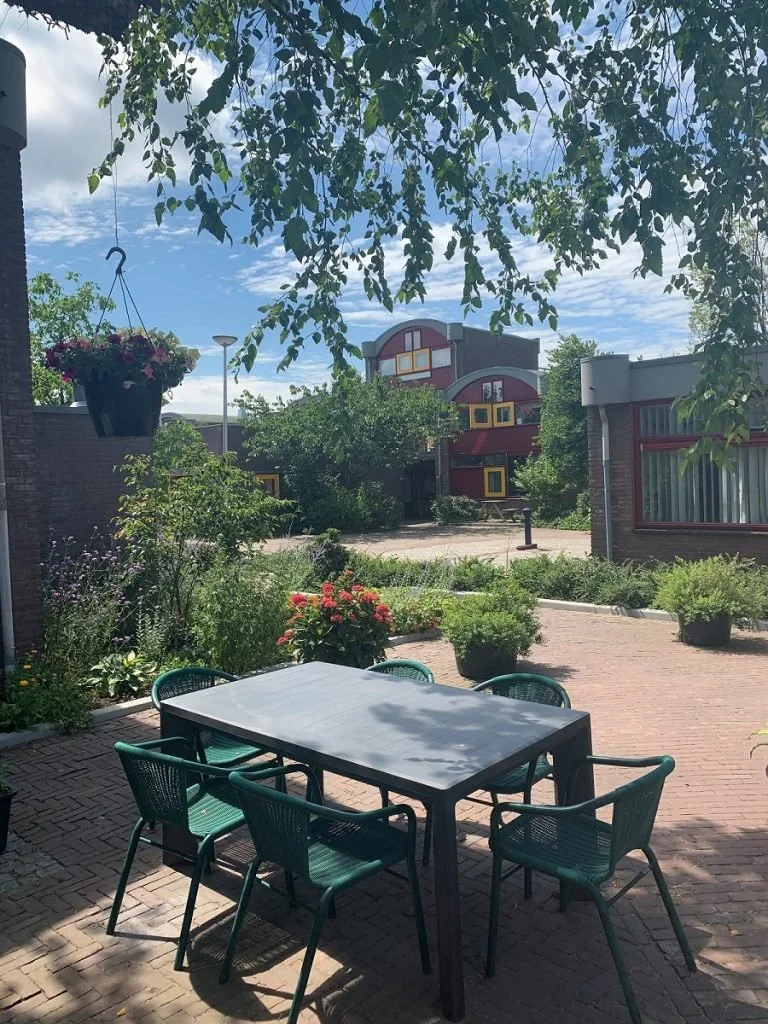 Afb. 8 | buitenruimte van de wandelstraat, met tuinmeubilair voor het huis en de waterpomp op het plein (foto:  , datering geschat 2016-2020, [23 april 2021]). 