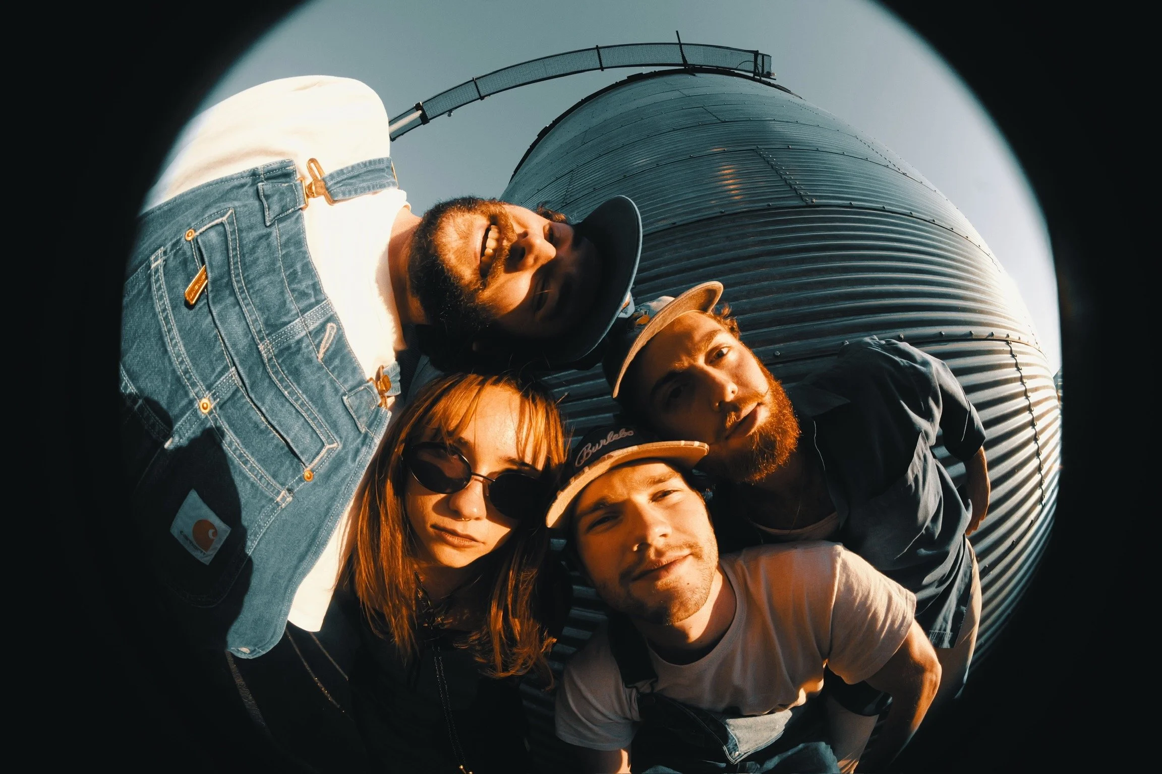 Group of five people dressed as astronauts standing against a yellow circular background.