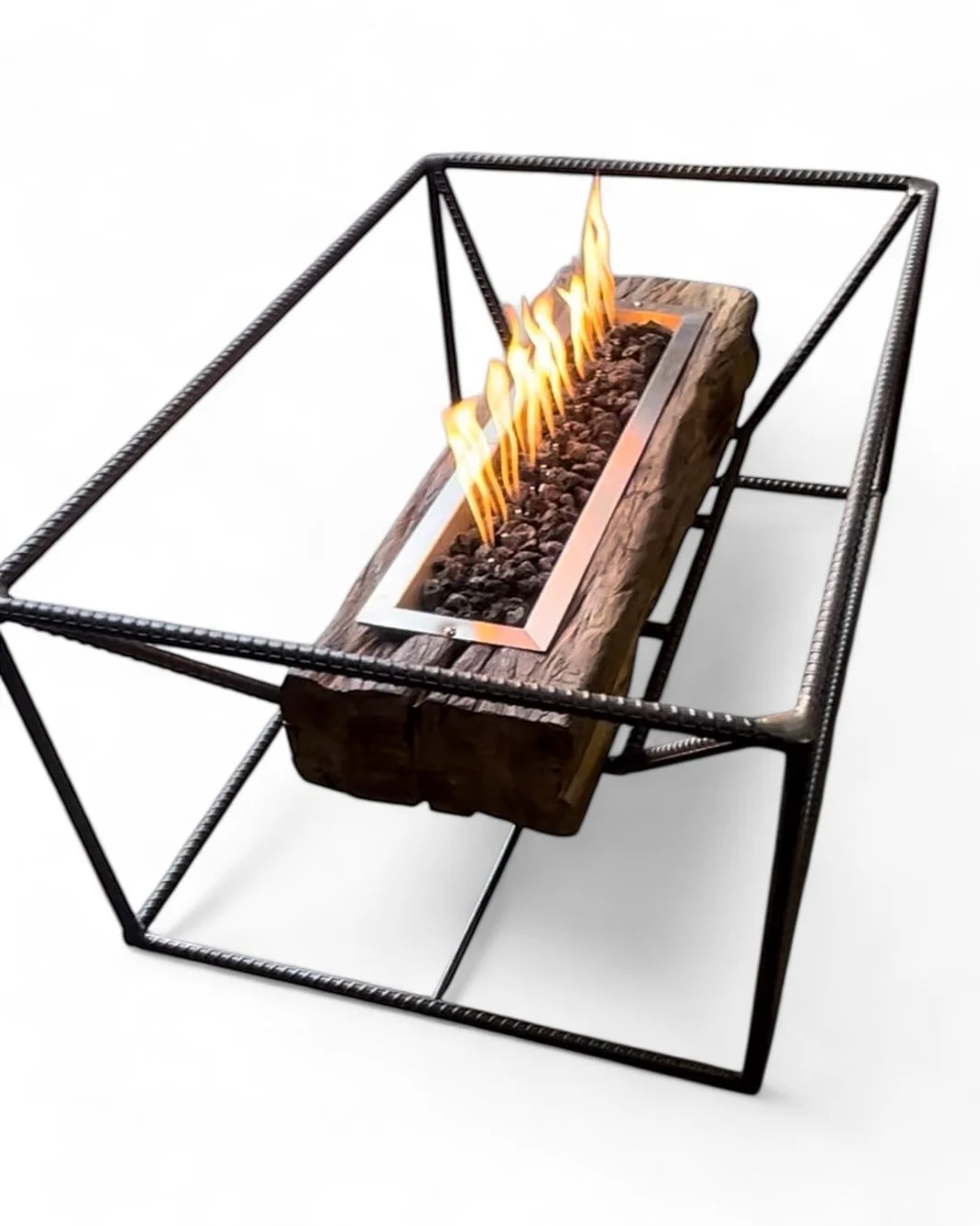 Modern tabletop fire feature with a rectangular fire pit filled with rocks, surrounded by a wooden border, inside a black metal geometric frame.