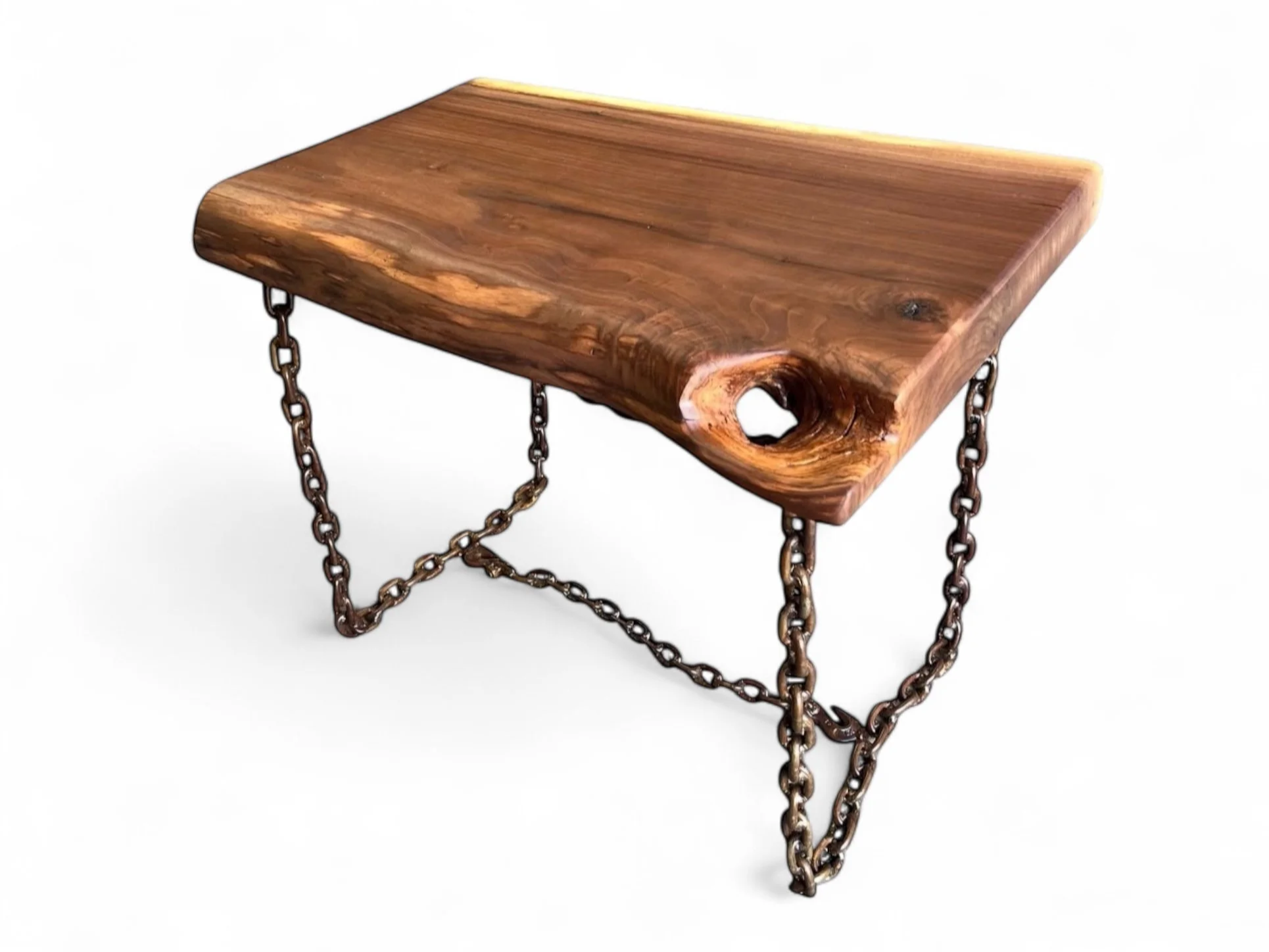 A small wooden table with metal chains as support legs, showcasing a natural wood grain finish and a hole in one corner.
