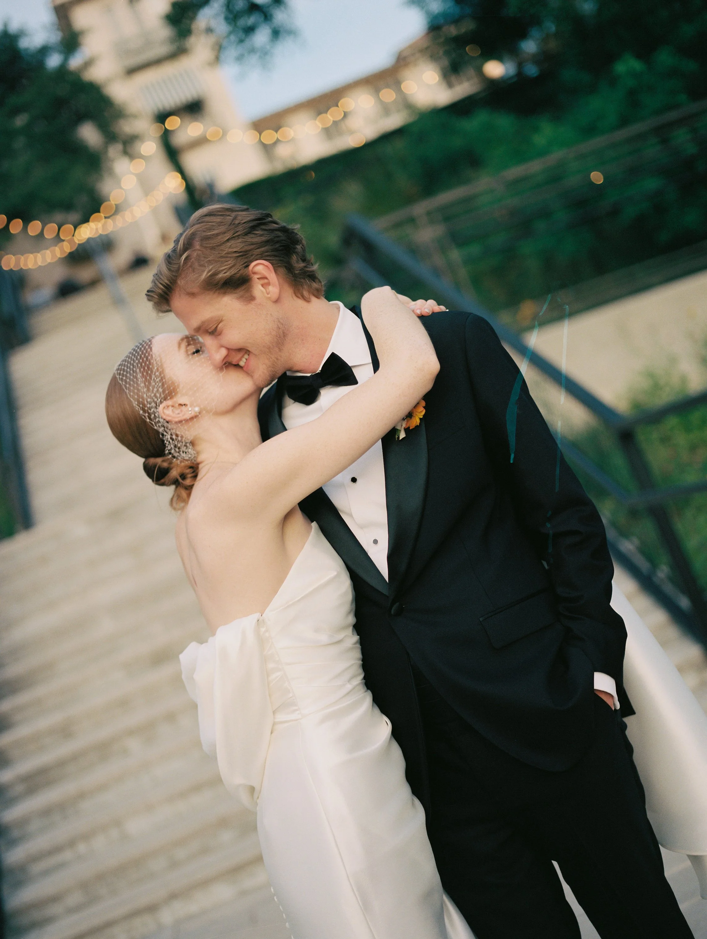 Bride and groom kissing at sunset photographed on the steps of Laguna Gloria in Austin, Texas.