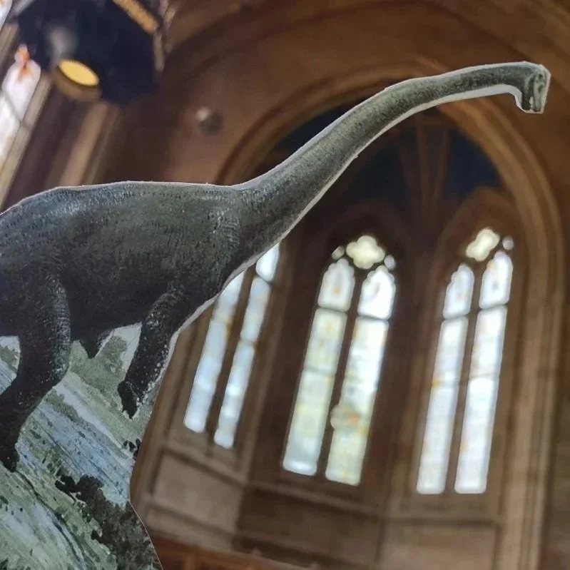 Paper dinosaur puppet in historic library.
