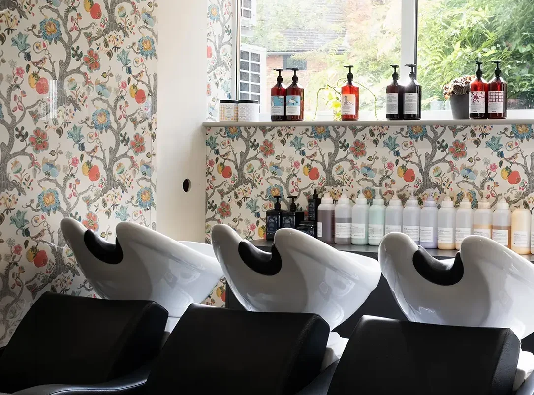 Albert Fields salon interior with hair wash stations, botanical wallpaper and professional haircare products.