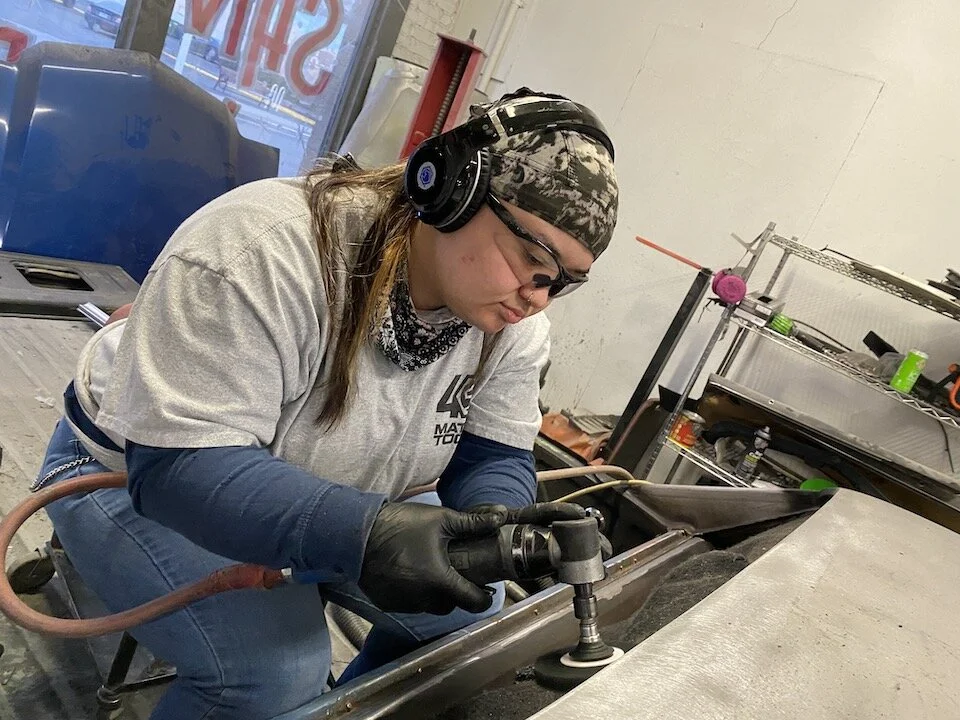 Stefanie Wilkinson grinds metal flat on the back of the cab of a ‘72 El Camino.