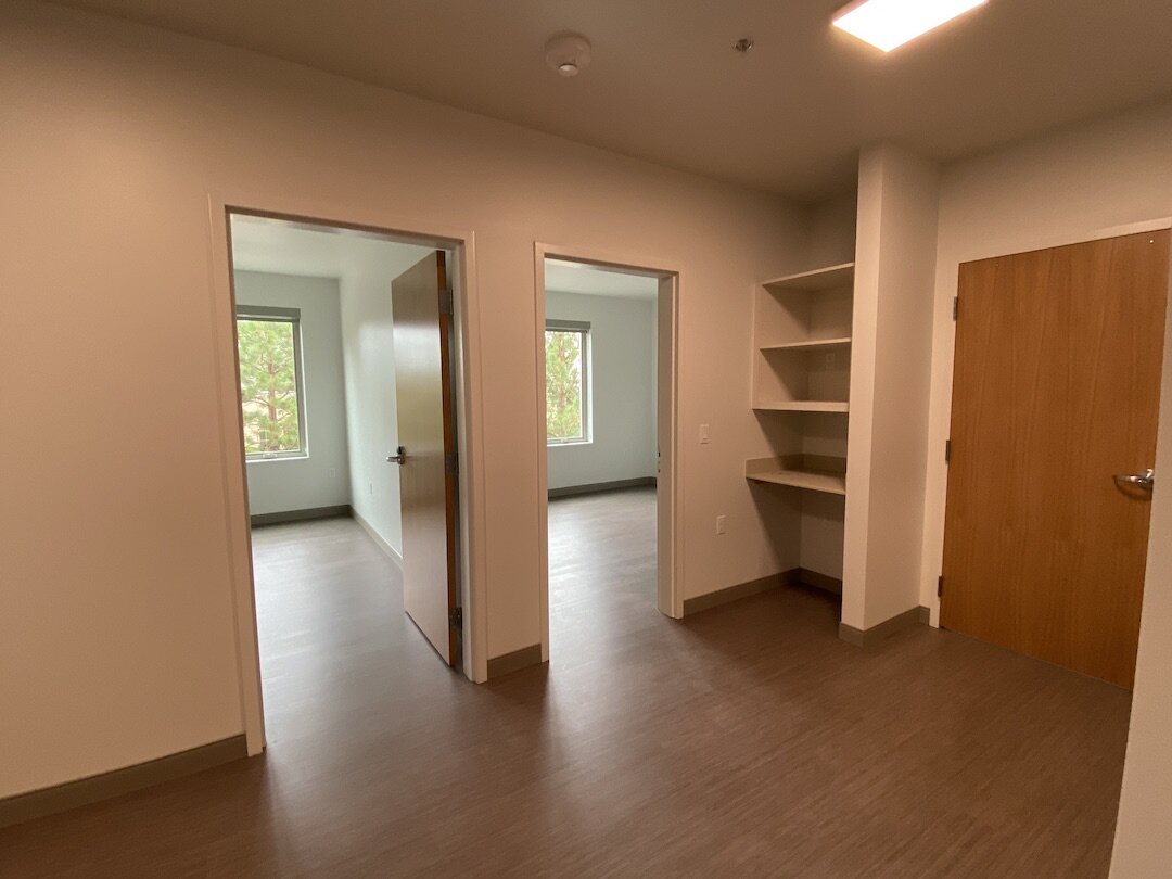 A view of the main area of a dorm room with entrances leading to bedrooms.