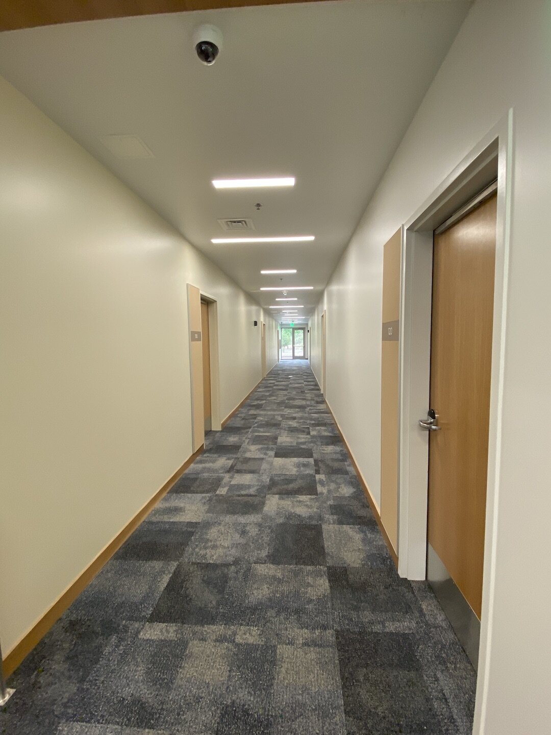 Looking long down the first floor hallway of Chinook Residence Hall. Blues and light wood tones set a good energy for study and social engagement.
