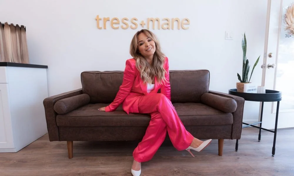 Yvette Gonzalez, featured in VoyageLA Magazine, seated in the Tress+Mane Hair Extension Salon in Hermosa Beach, showcasing the luxury salon where she specializes in NBR®, hand-tied hair extensions, and custom color.