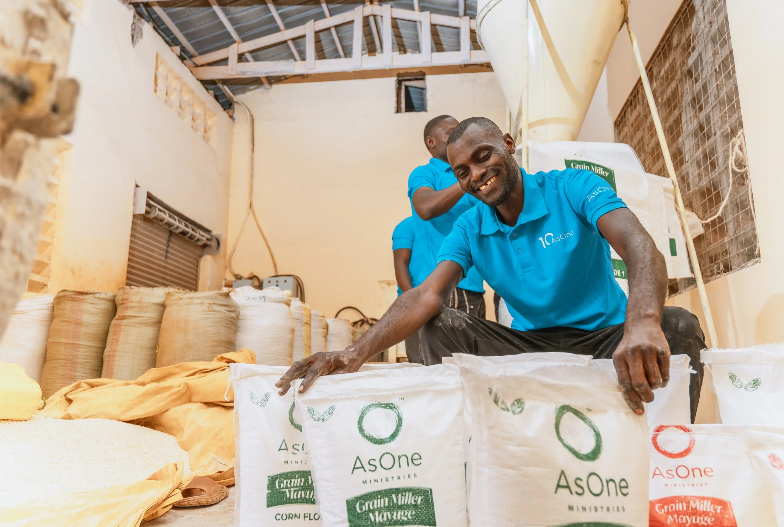 AsOne staff member at Mayuge Grain Millers packing branded corn flour bags