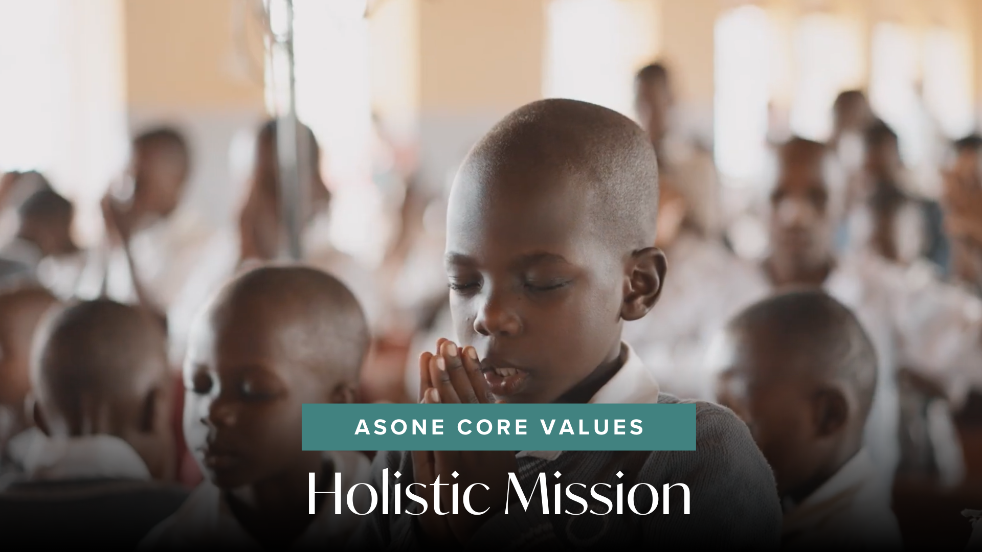 AsOne Core Values banner, 'Holistic Mission,' showing a young student praying with hands clasped among classmates