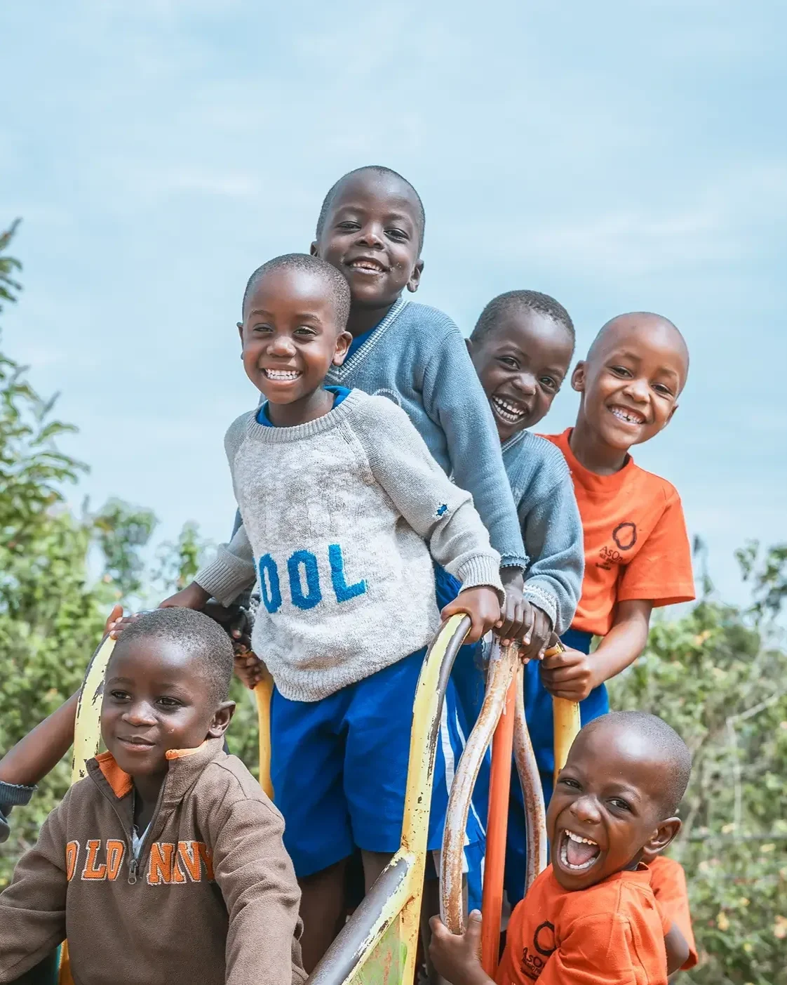 AsOne Nursery & Primary School, Idudi students smiling and playing together on a slide