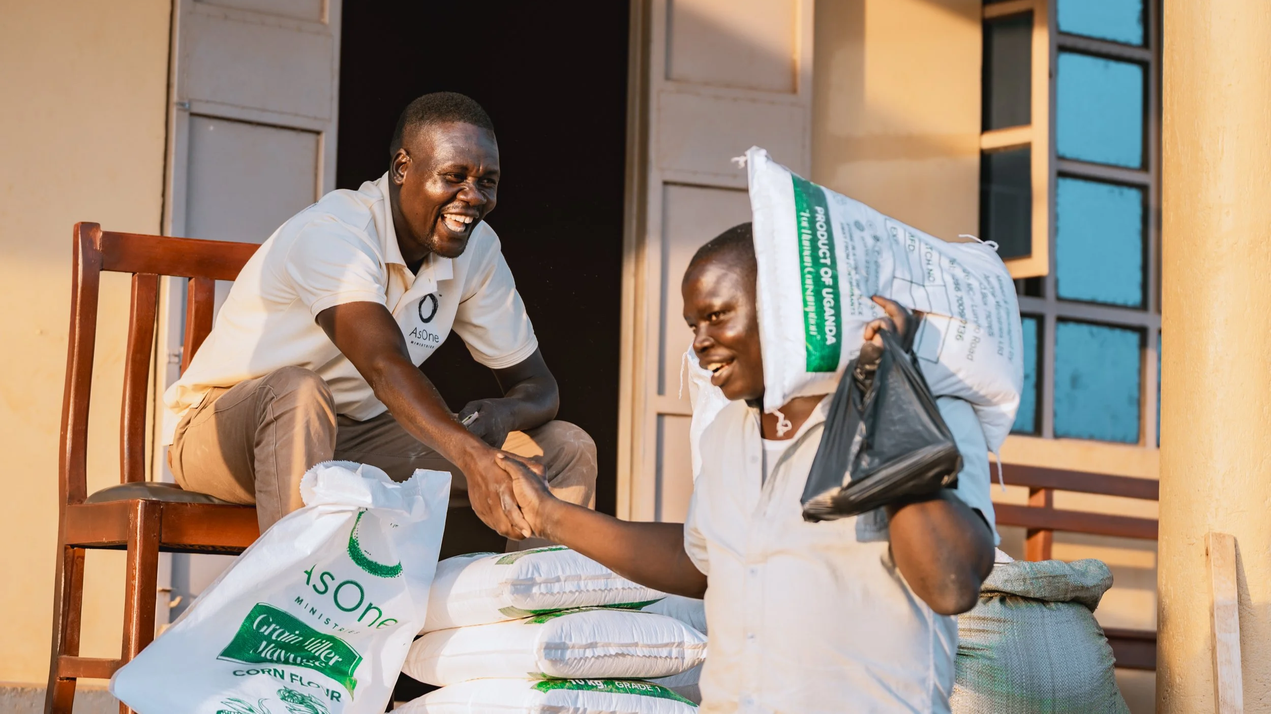 AsOne staff member of Mayuge Grain Millers shaking hands with a customer after a corn flour purchase