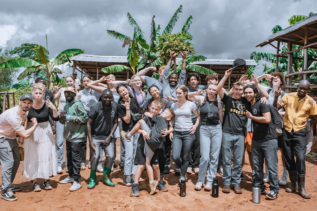 Group photo of AsOne immersion trip participants and staff posing during a farm visit in Idudi