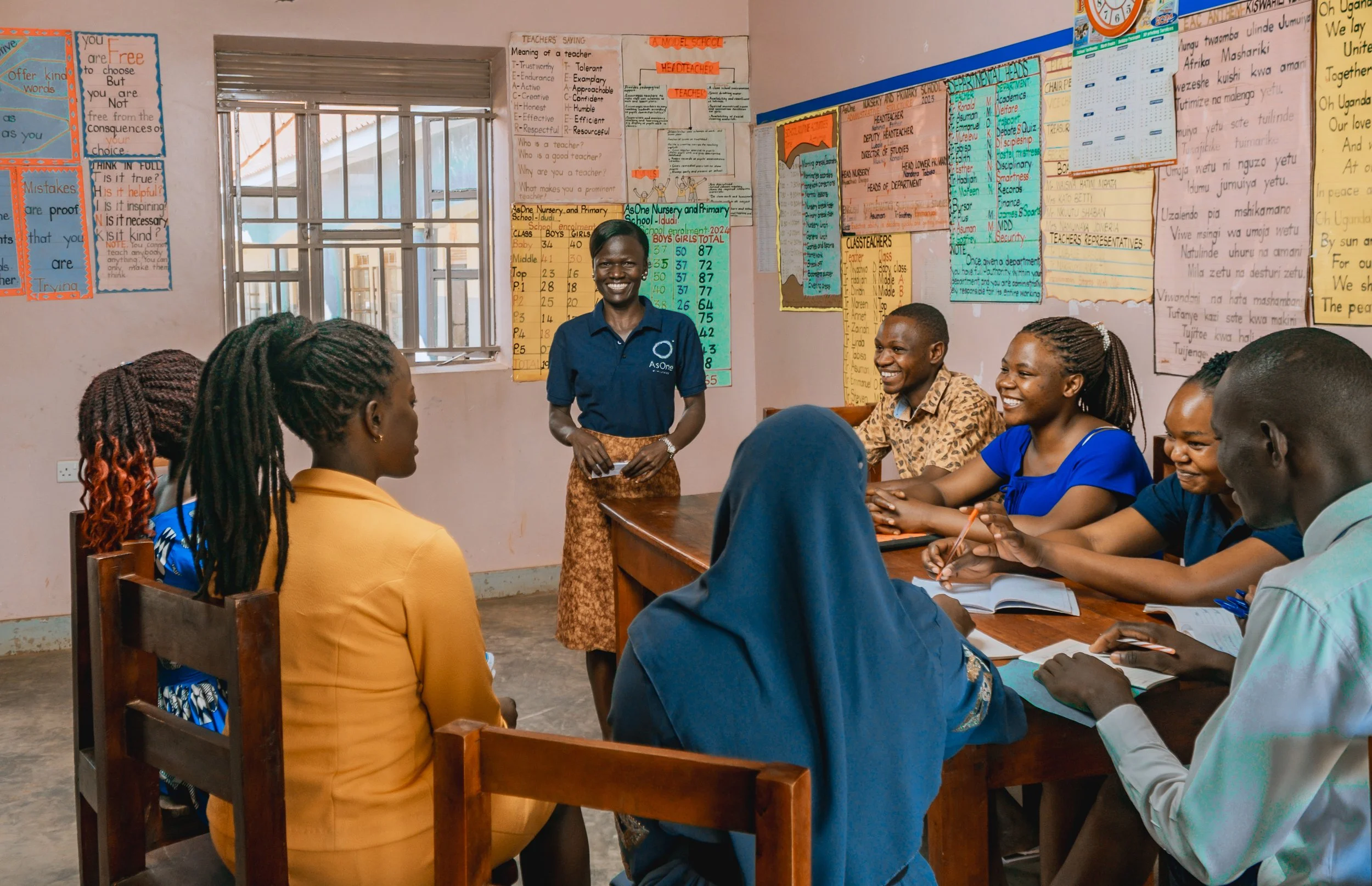 Esther, an AsOne staff member, leading a discussion with a group of people in a classroom at AsOne Nursery and Primary School, Idud