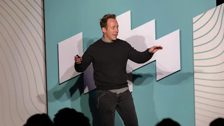 Praxis Journal feature 'Andrew DeVaney // AsOne Ministries,' showing Andrew DeVaney presenting on stage
