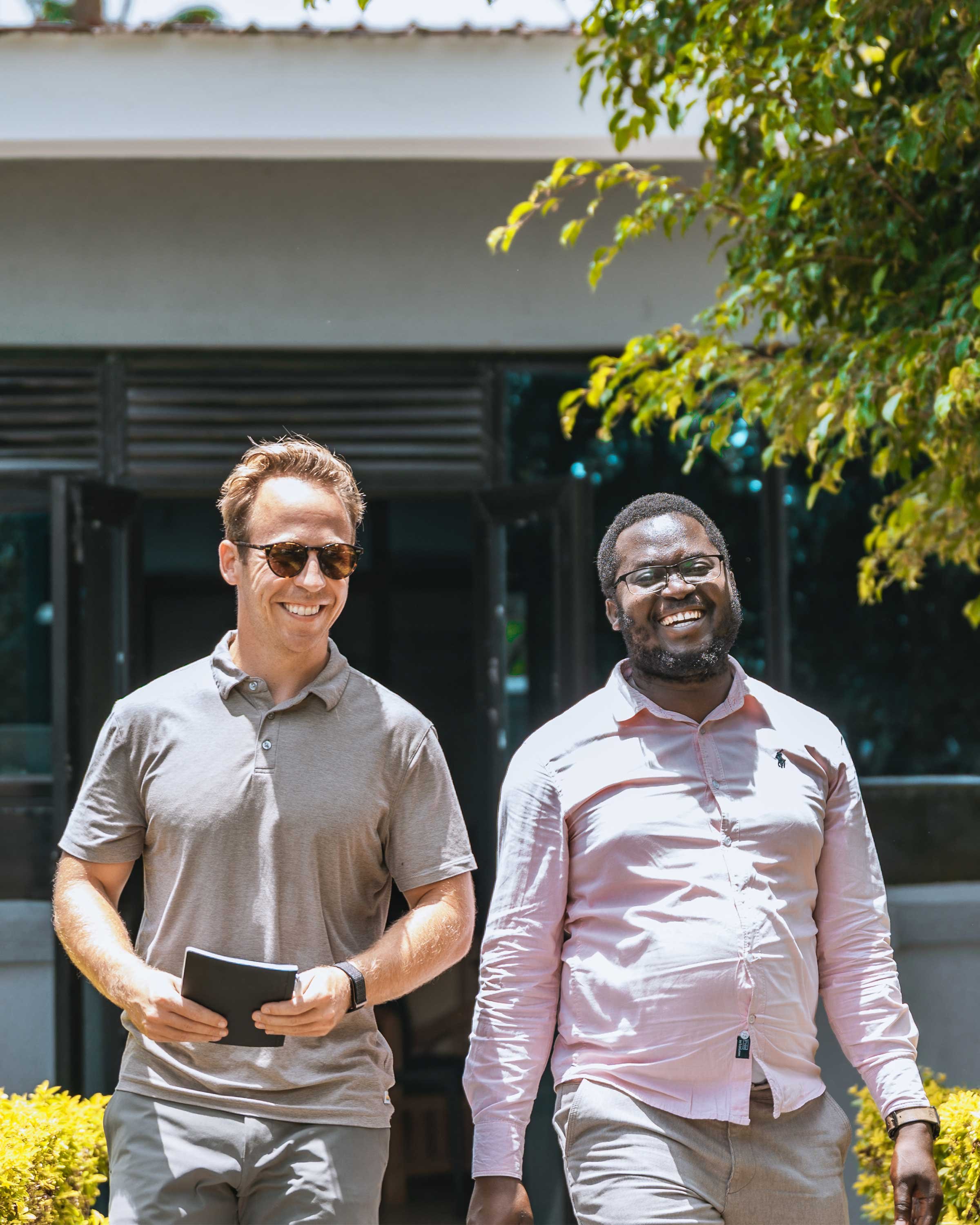 Andrew DeVaney and Henry Iwumbwe, AsOne co-founders, smiling outdoors
