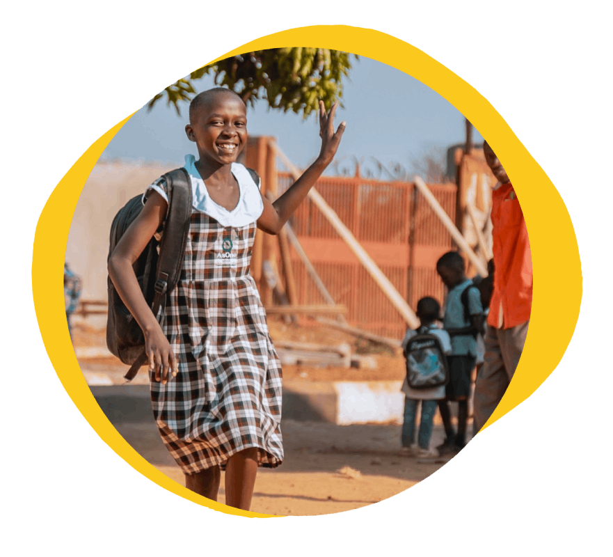 Joy, an AsOne student in Serere, smiling and waving with her backpack on