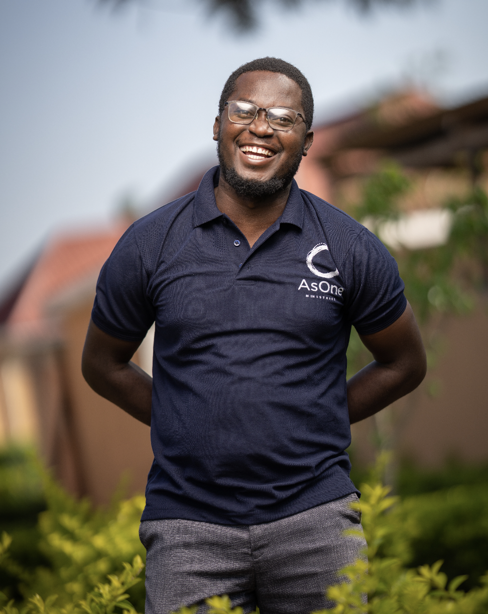 Henry Iwumbwe, Executive Director — Uganda, smiling outdoors in an AsOne polo shirt