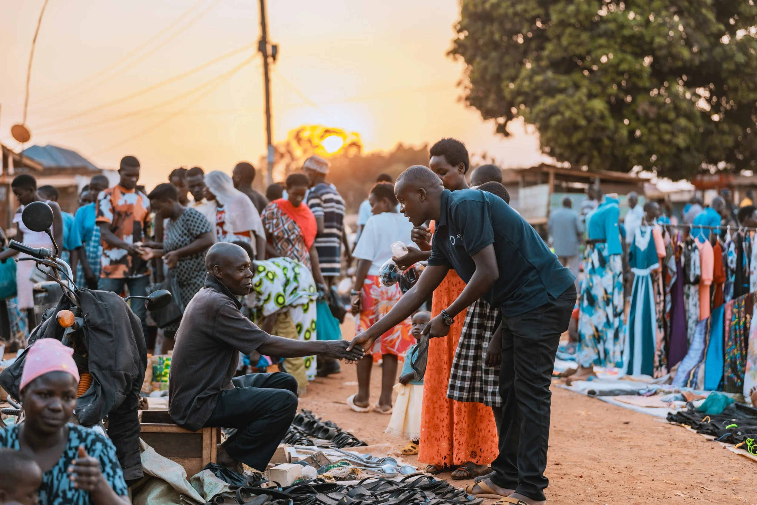 Deogracious Waisswa, AsOne community director, shaking hands with a man during community outreach in Mayuge, Uganda