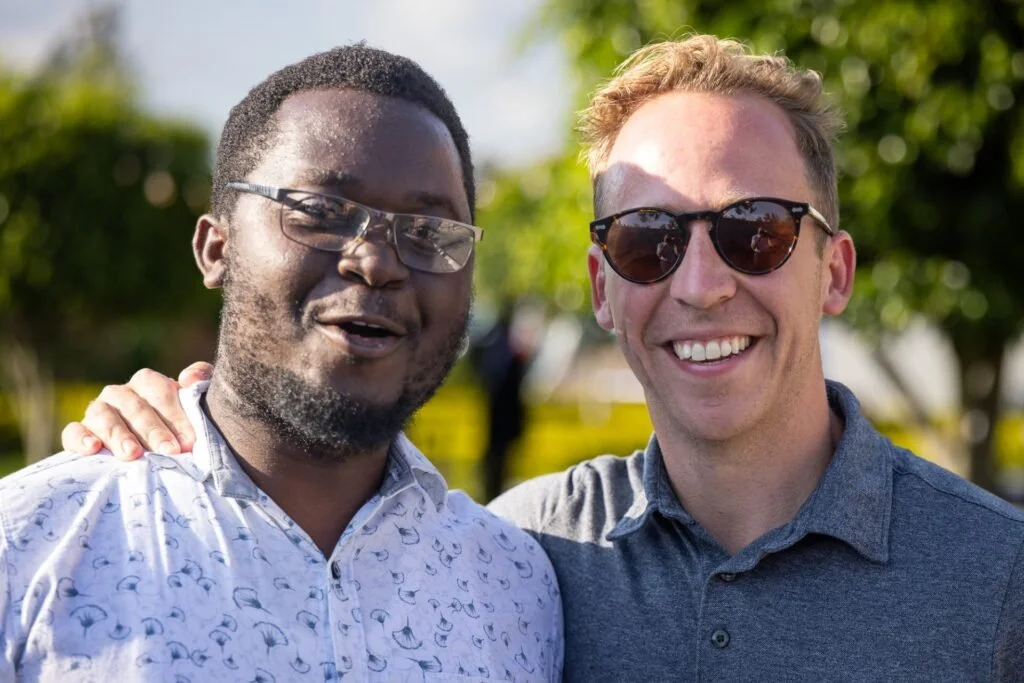 Denver Seminary blog feature 'Alumni Spotlight: Andrew DeVaney — Home in the Hard Places,' showing Andrew DeVaney with Henry Iwumbwe, Co-Founder of AsOne Ministries