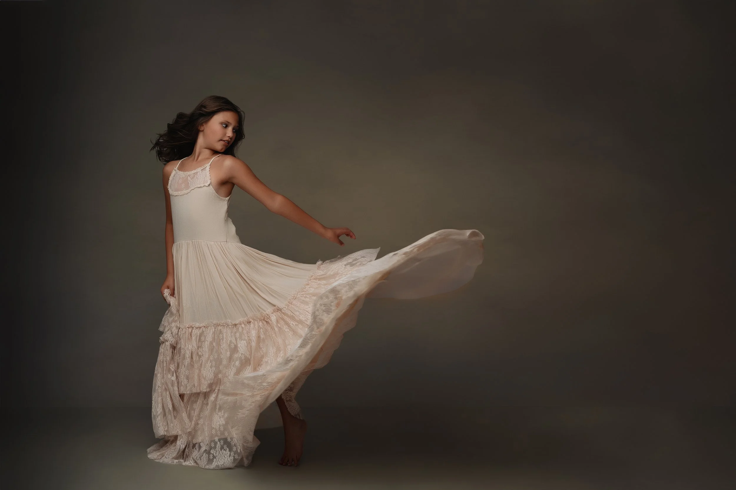 Artistic portrait of a younfg girl twirling in a flower dress. This image captures the movement and joy of childhood, with a touch of elegance. Photography by Sommer Ortiz, specializing in creative child portraits.