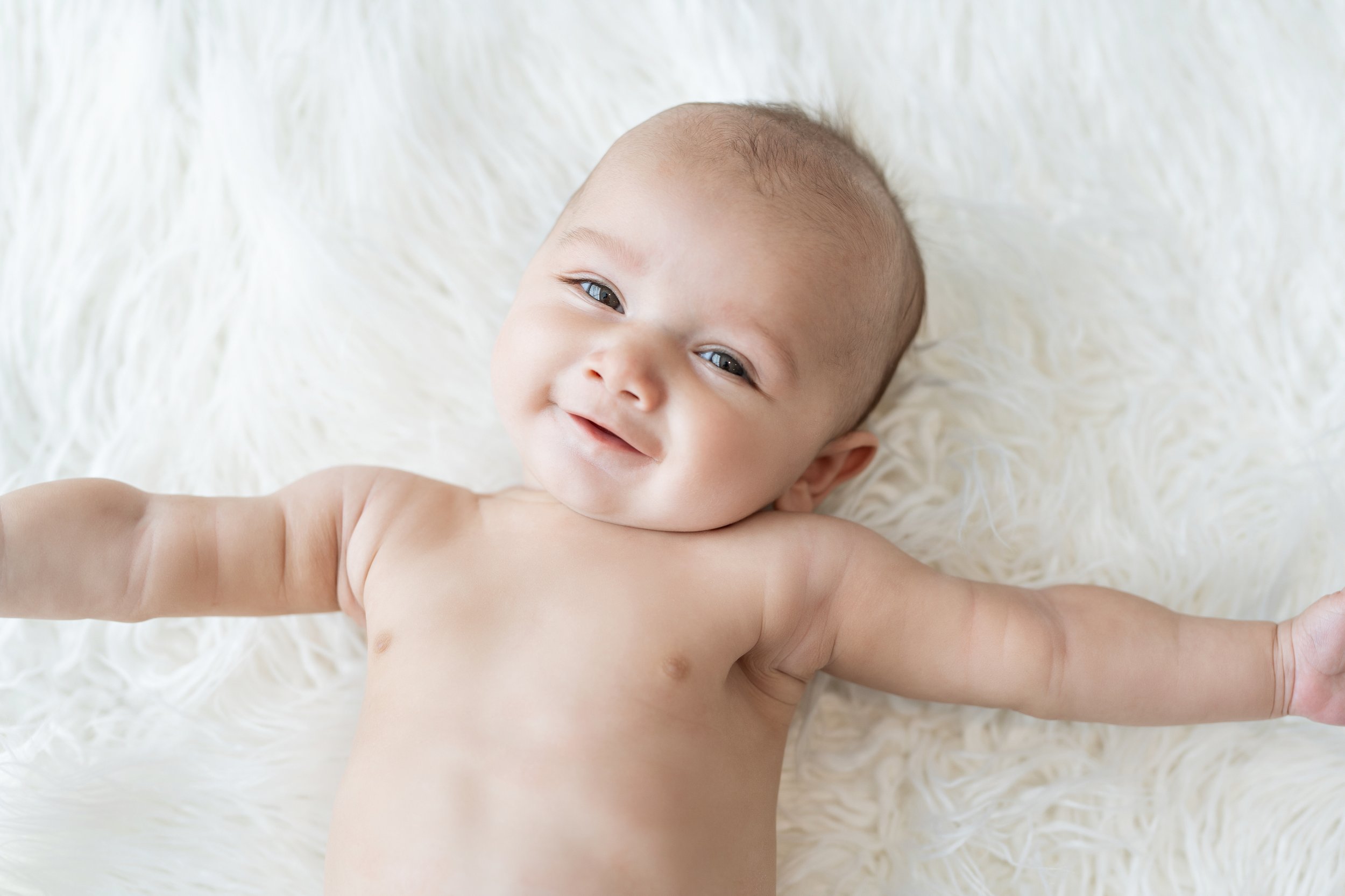 A delightful portrait of a baby smiling on a fluffy white blanket in North Myrtle Beach,South Carolina, their joydul spirit captured in a natural , relaxed pose. This image encapsulates the innocence and happiness of early childhood, perfect for fami