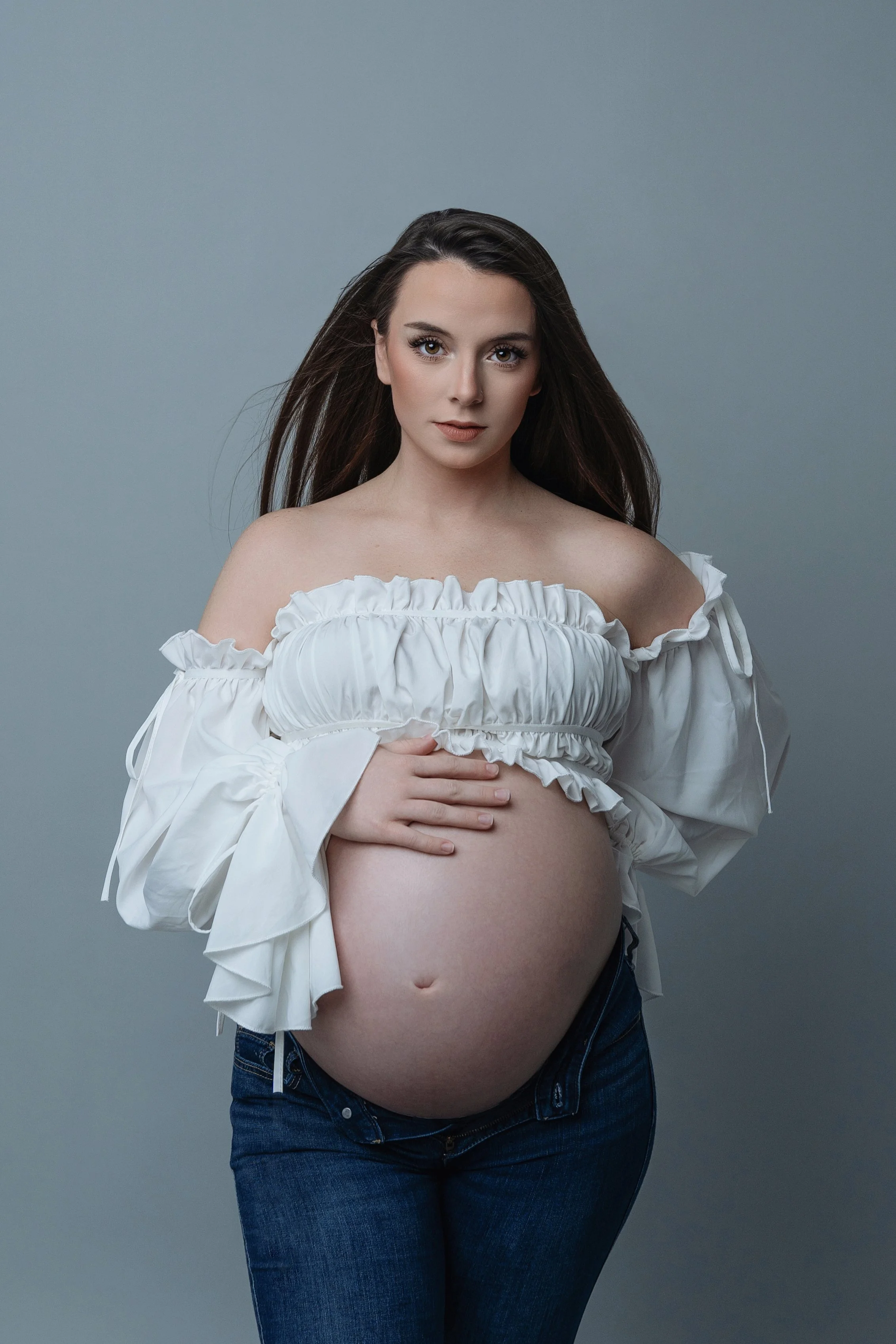 Maternity portrait featuring a poised expectant mother in North Myrtle Beach, her pregnancy highlighted by a chic off-the-shoulder ruffled blouse paired with classic denim. this image reflects the elegance and anticipation of motherhood, perfect for 
