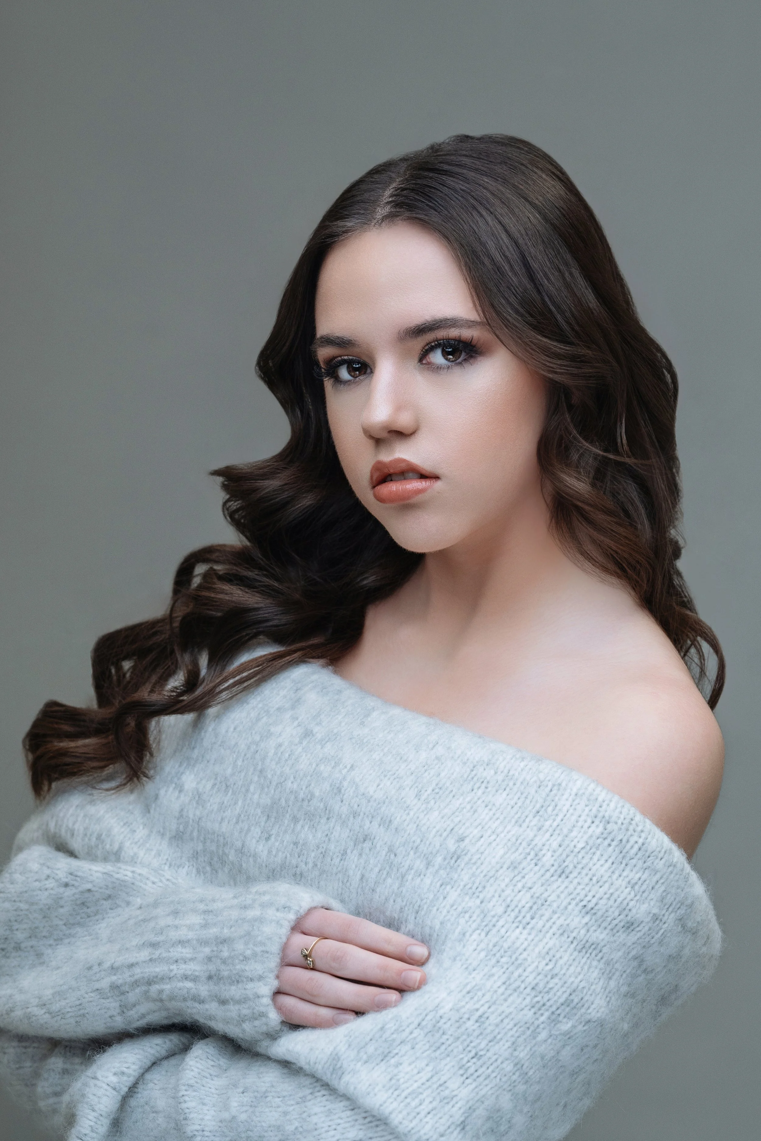 Soft and sophisticated portrait of a young woman in Myrtle Beach, draped in a cozy gray sweater that complements her cascading dark curls and piercing gaze. This image showcases the photographer's expertise in capturing the essence of contemporary fe