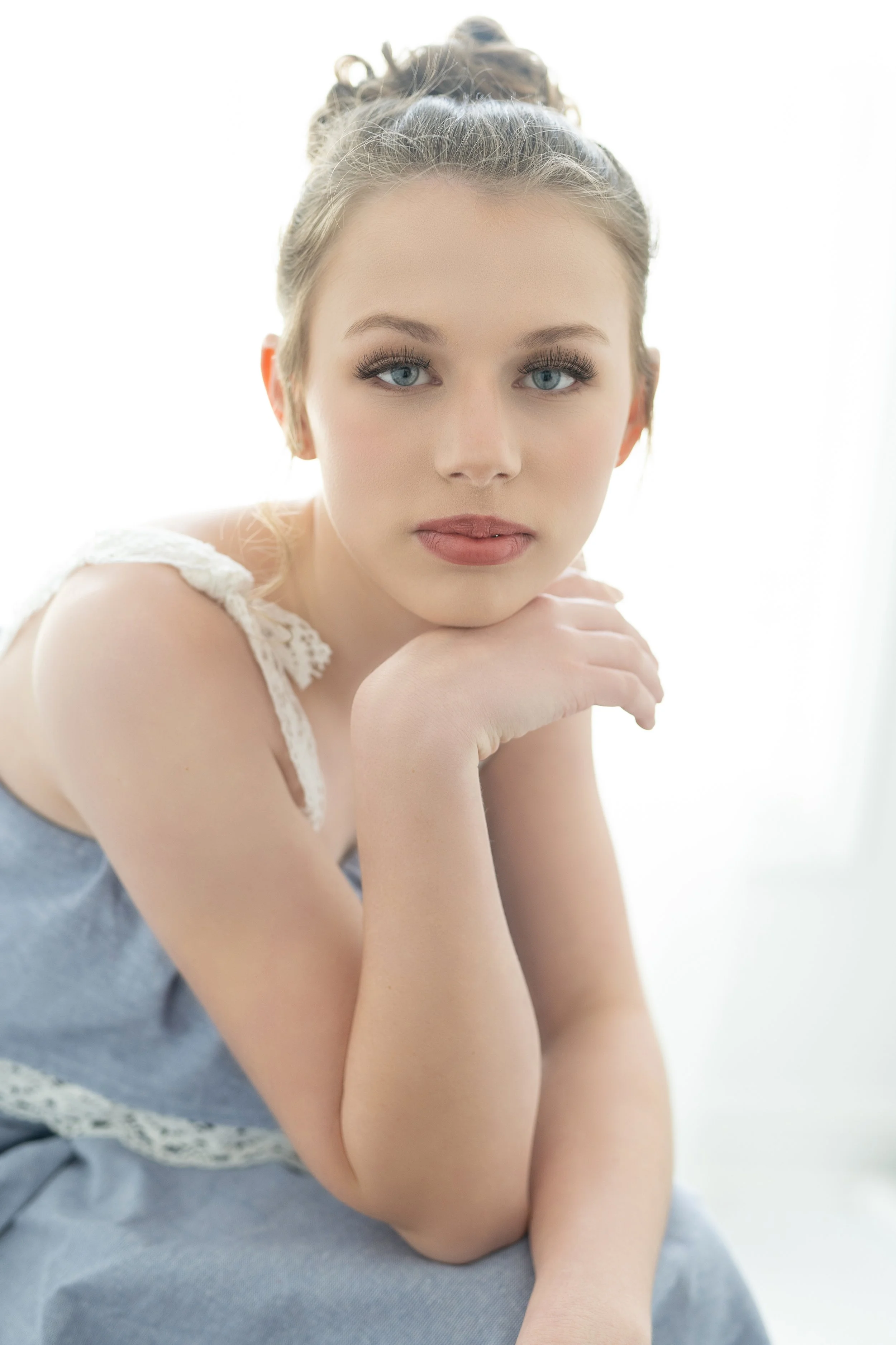 Elegant portrait of a young woman in North Myrtle Beach, exuding sophistication in a lace-detailed dress. Her thoughtful gaze and relaxed pose in soft, natural light create a timeless beauty ideal for senior portraits or personal branding.