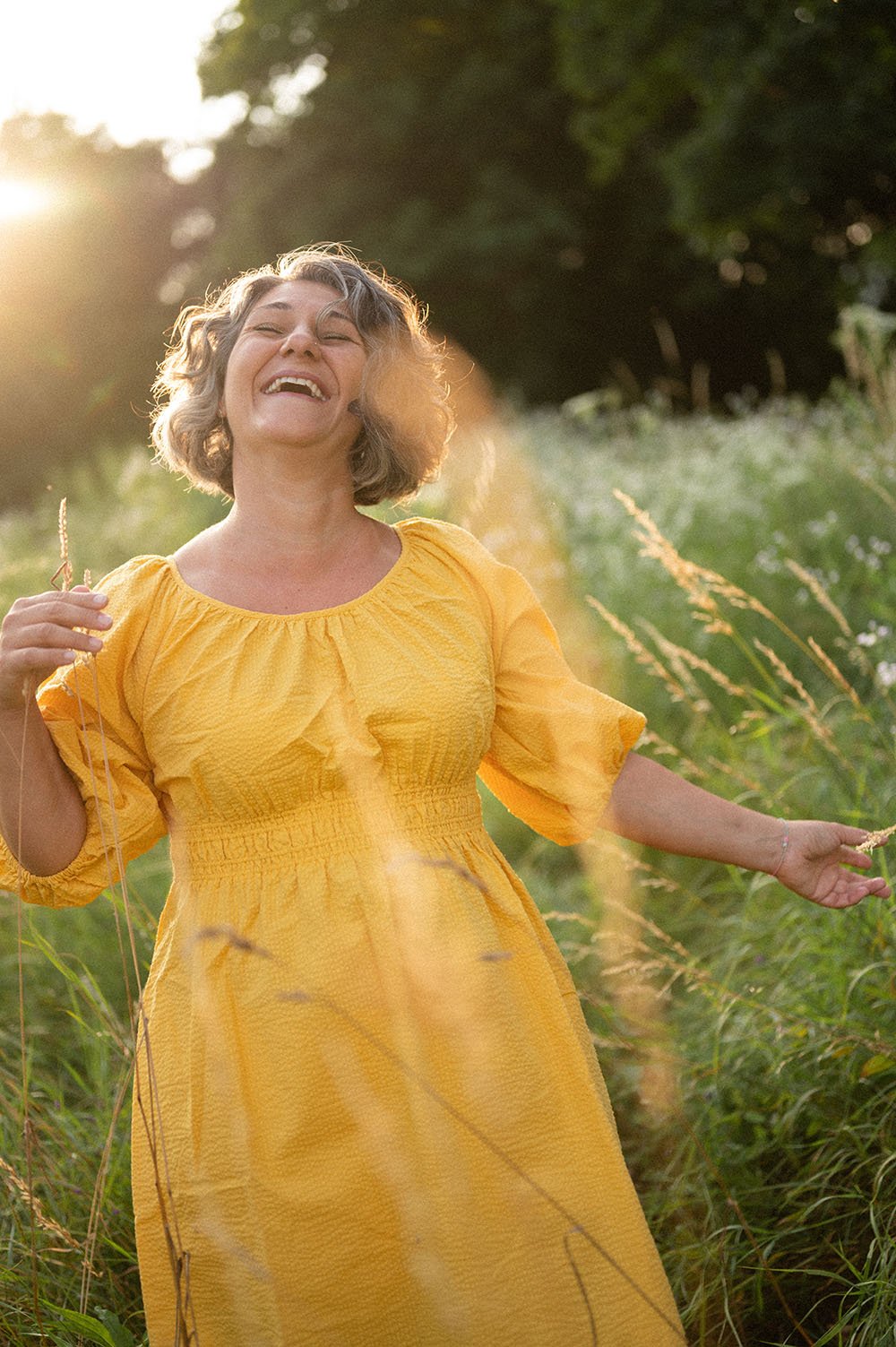 Donna con vestito giallo che ride al tramonto