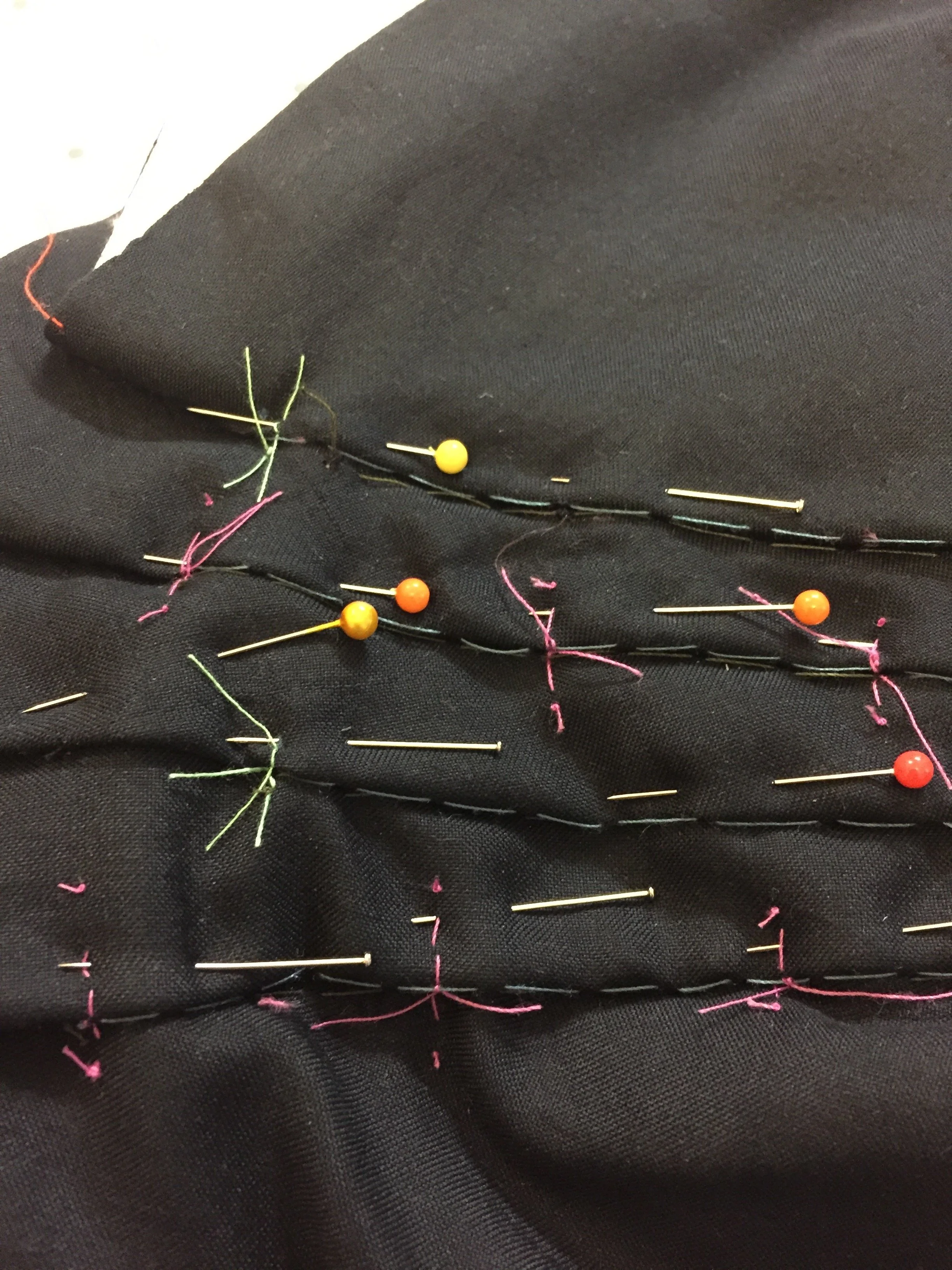 Much of the temporary hand stitching to hold the fabric in place during production is removed before the garment is completed.