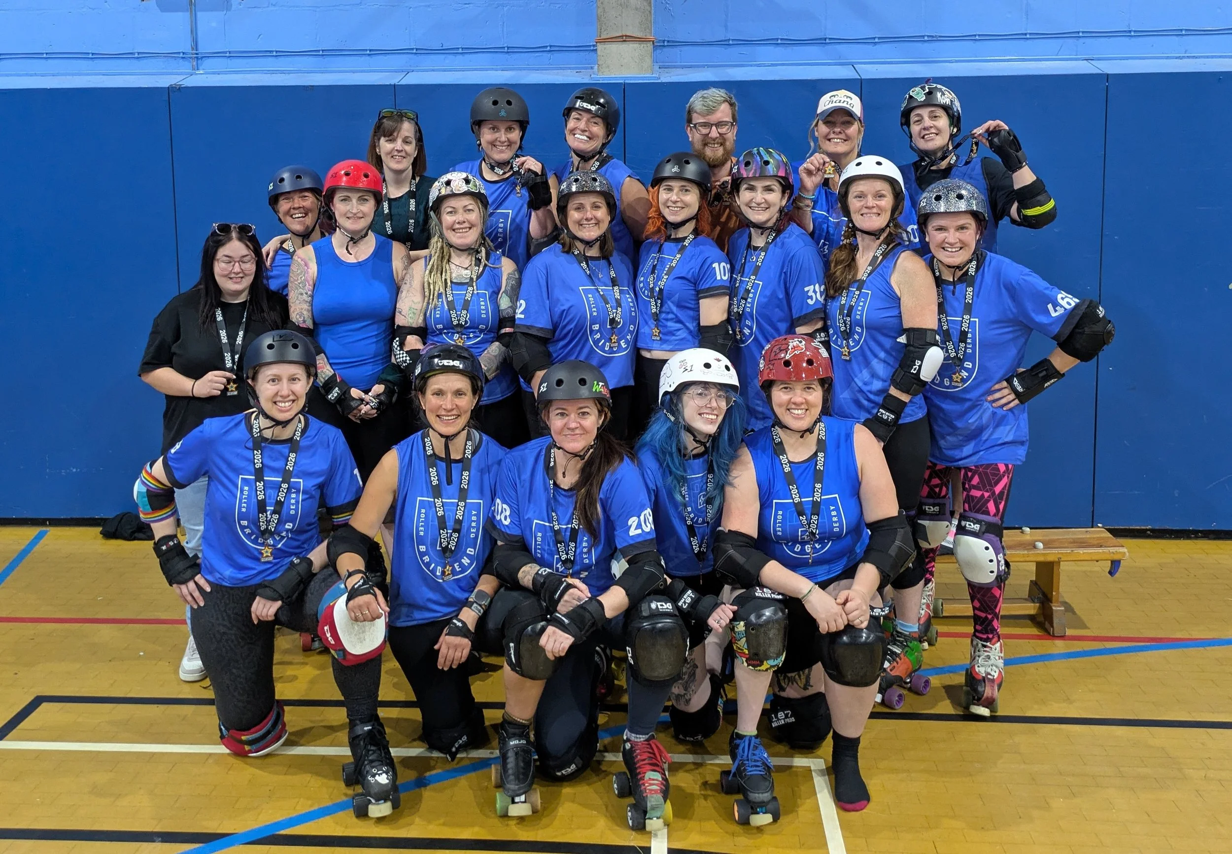 Bridgend Roller Derby team wearing their uniforms, all smiling and holding their medals for winning the Five Nations championships tier they were in.